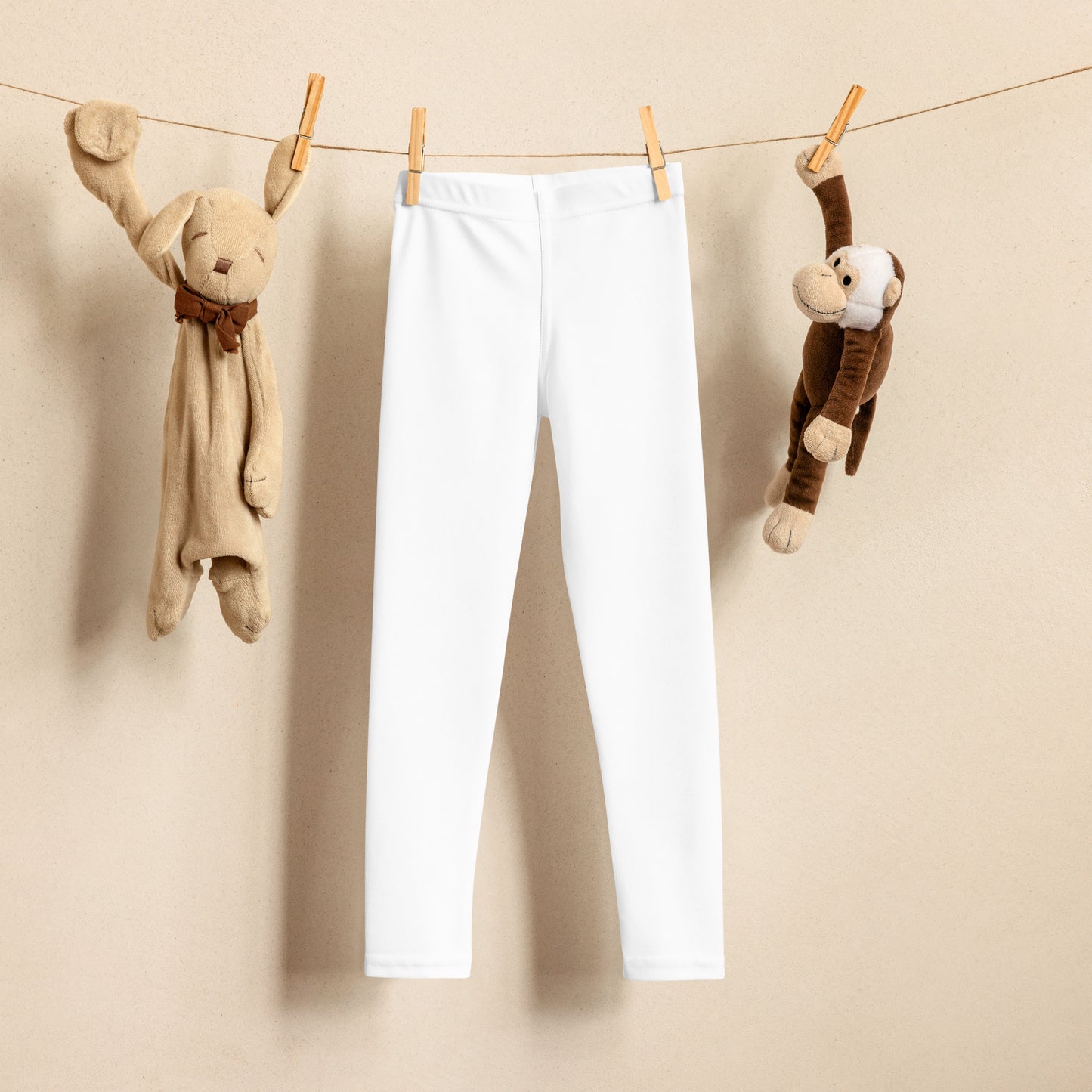 A pair of white kids' leggings hanging on a clothesline with two stuffed animals hanging on either side.