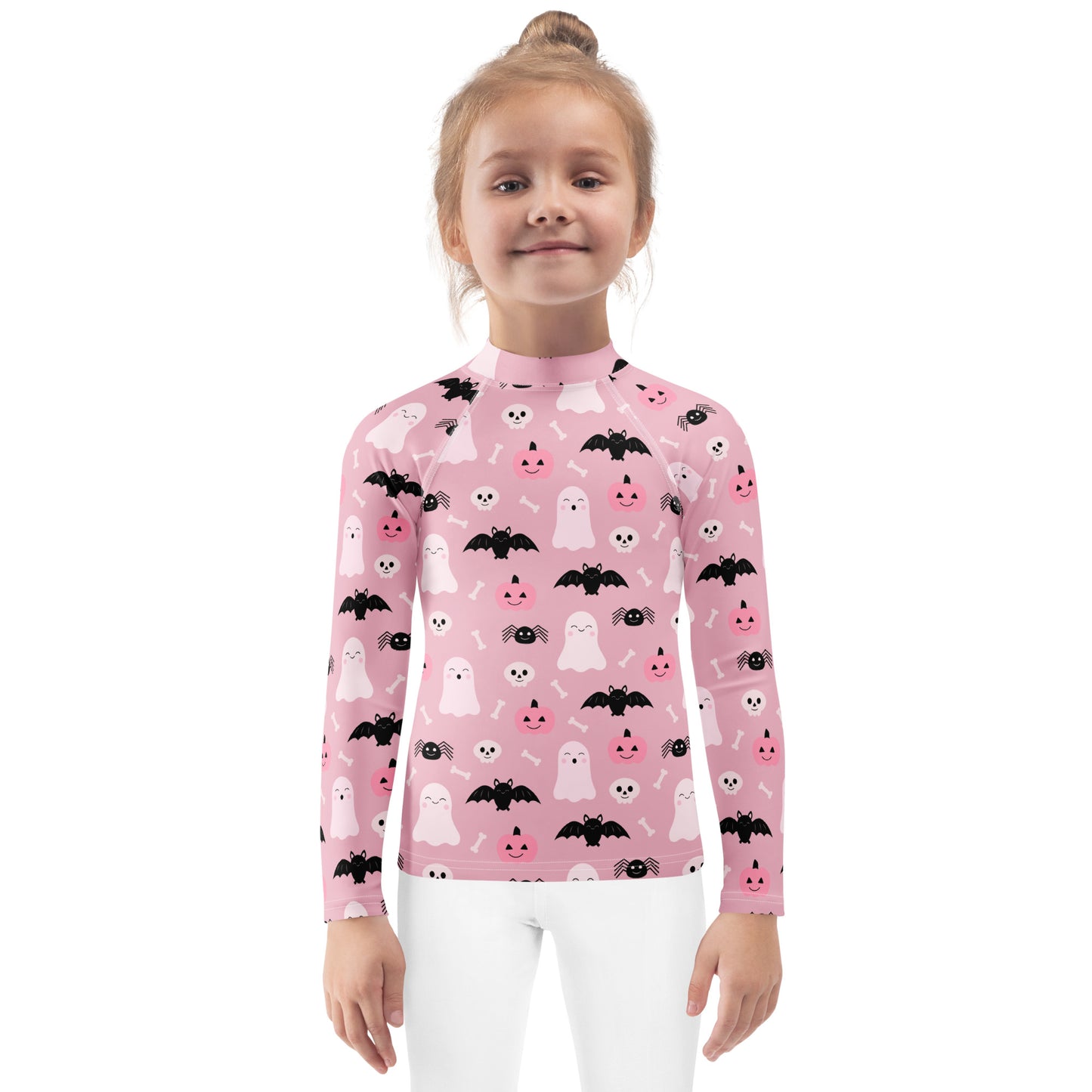 Girl wearing a pink Halloween-themed rash guard shirt with ghosts, bats, and pumpkins on a white background.