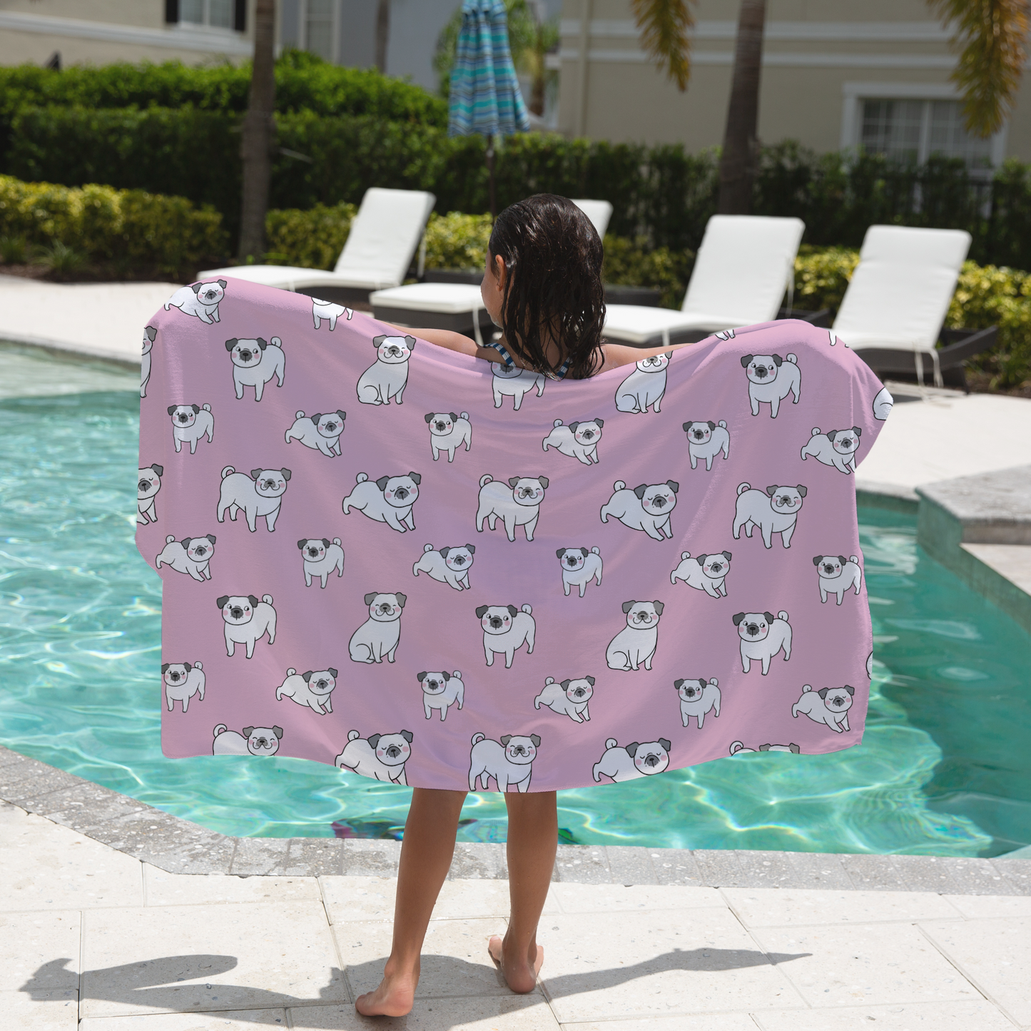 Girl holding a pink towel with dog patterns by a pool
