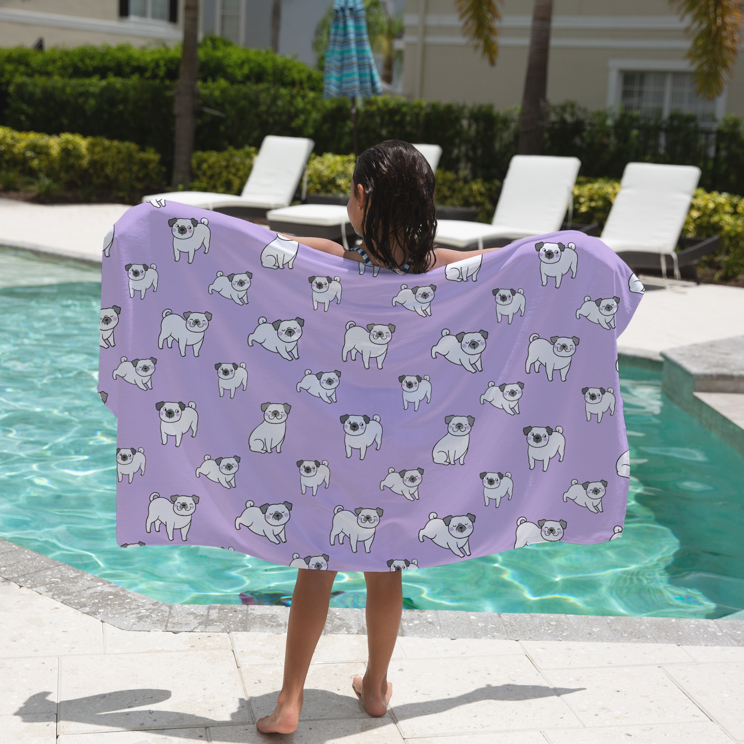 Girl holding a purple towel with dog patterns by a pool