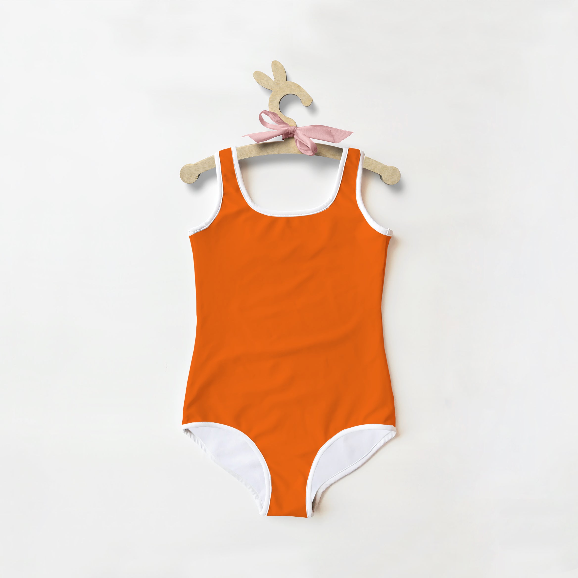 Girls buttery soft orange one-piece swimsuit with white trim and pink ribbon on hanger with UPF 50+ protection