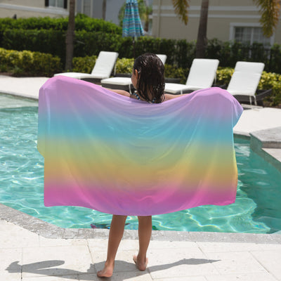 A vibrant rainbow-colored girls bright rainbow towel with smooth flowing fabric design for beach use