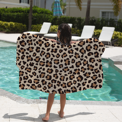 Child holding a leopard print towel by a pool