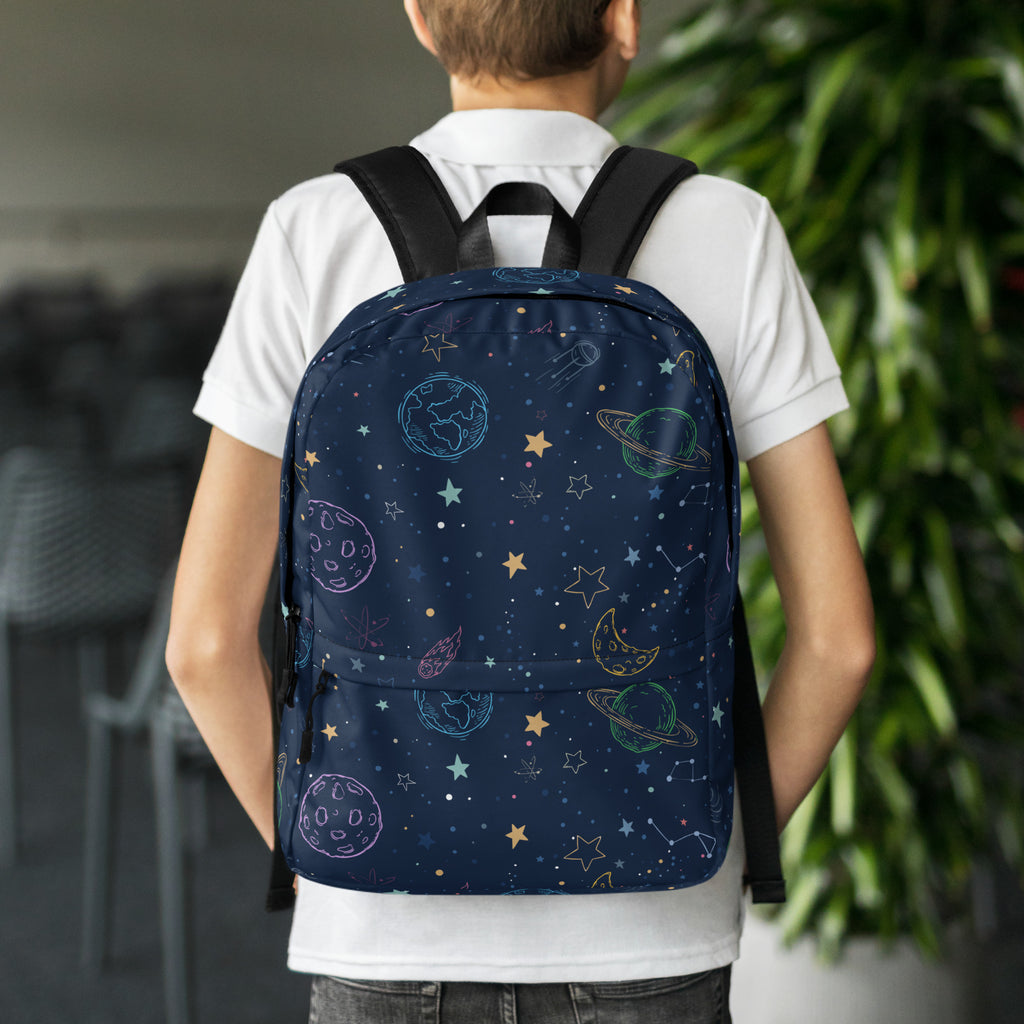 A navy blue kids backpack with a colorful cosmic design of outlined planets stars and pastel constellations