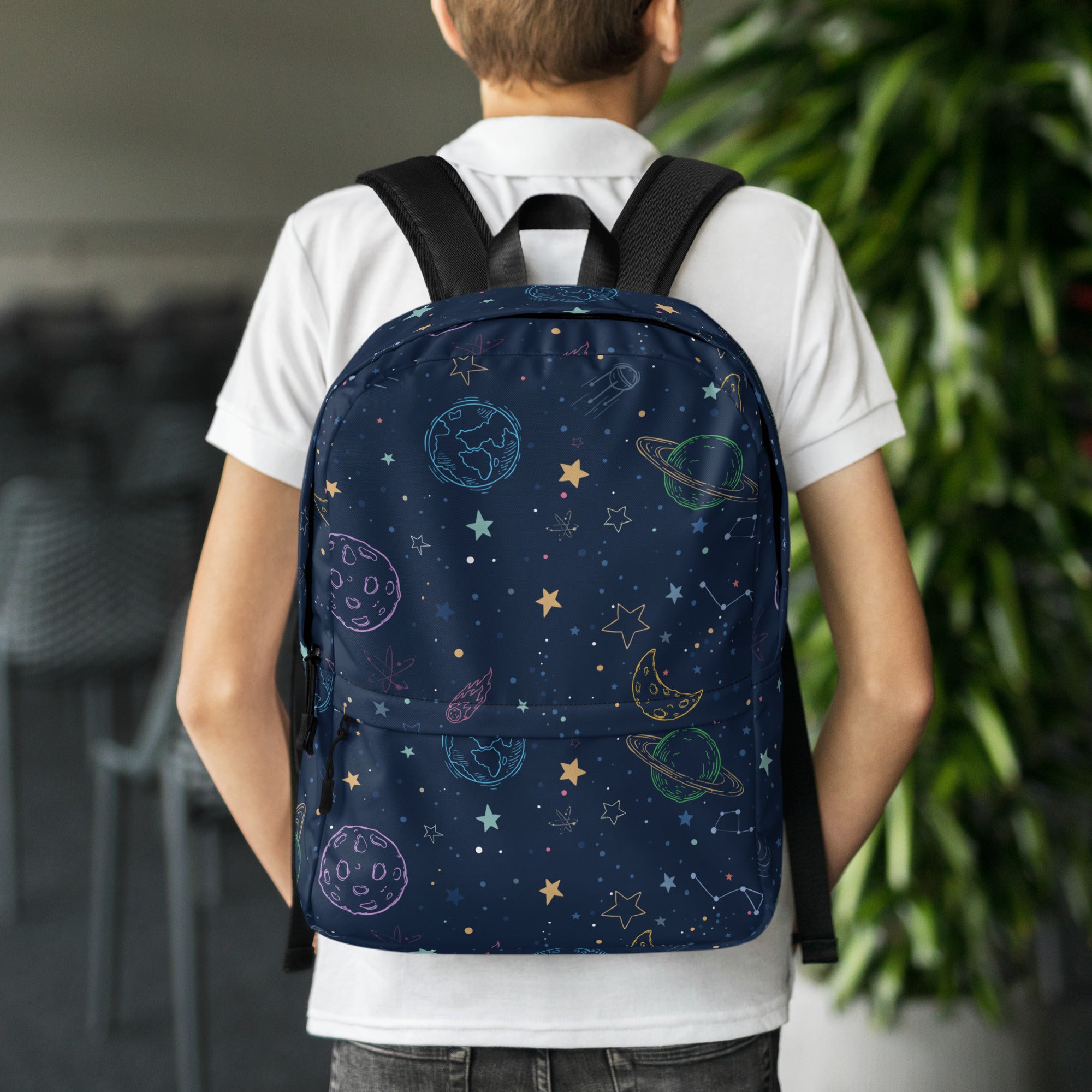 A navy blue kids backpack with a colorful cosmic design of outlined planets stars and pastel constellations