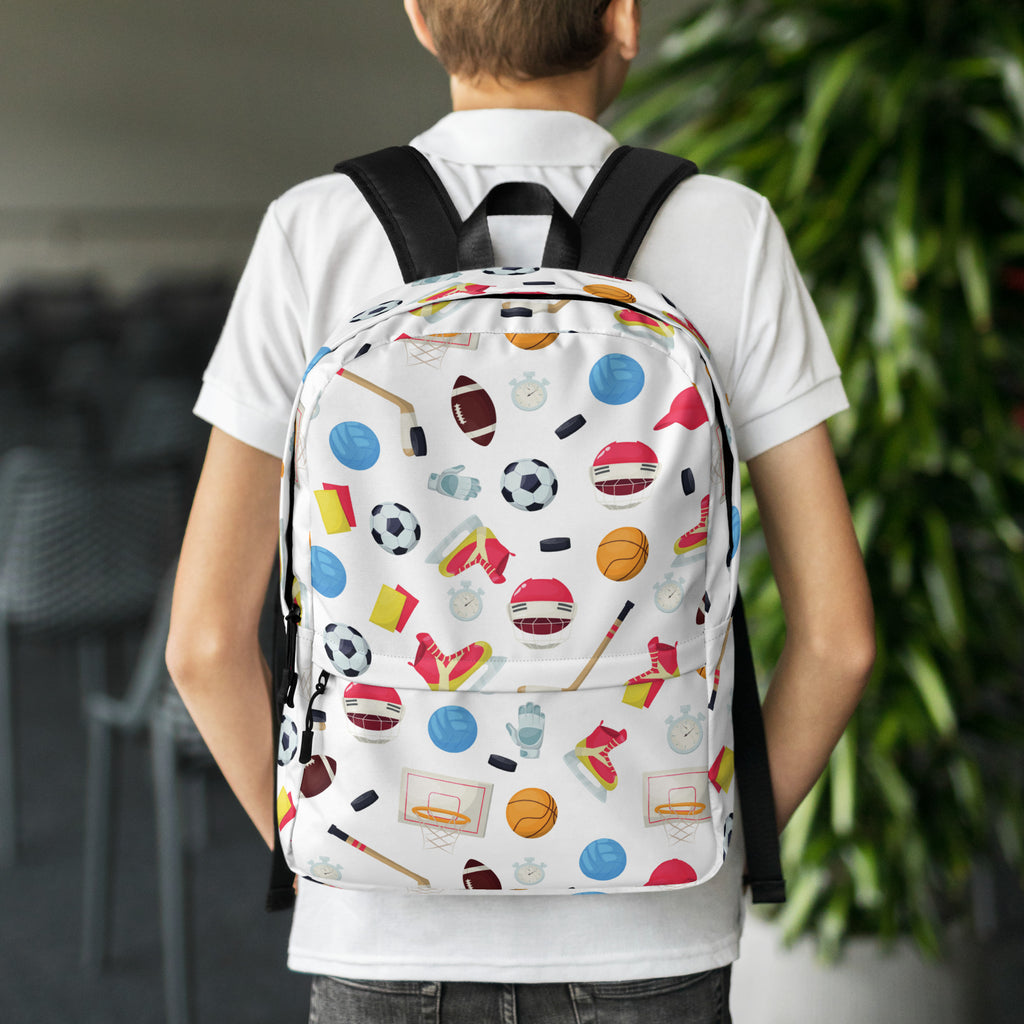 White kids sports themed backpack with black straps and colorful soccer ball basketball and hockey puck icons