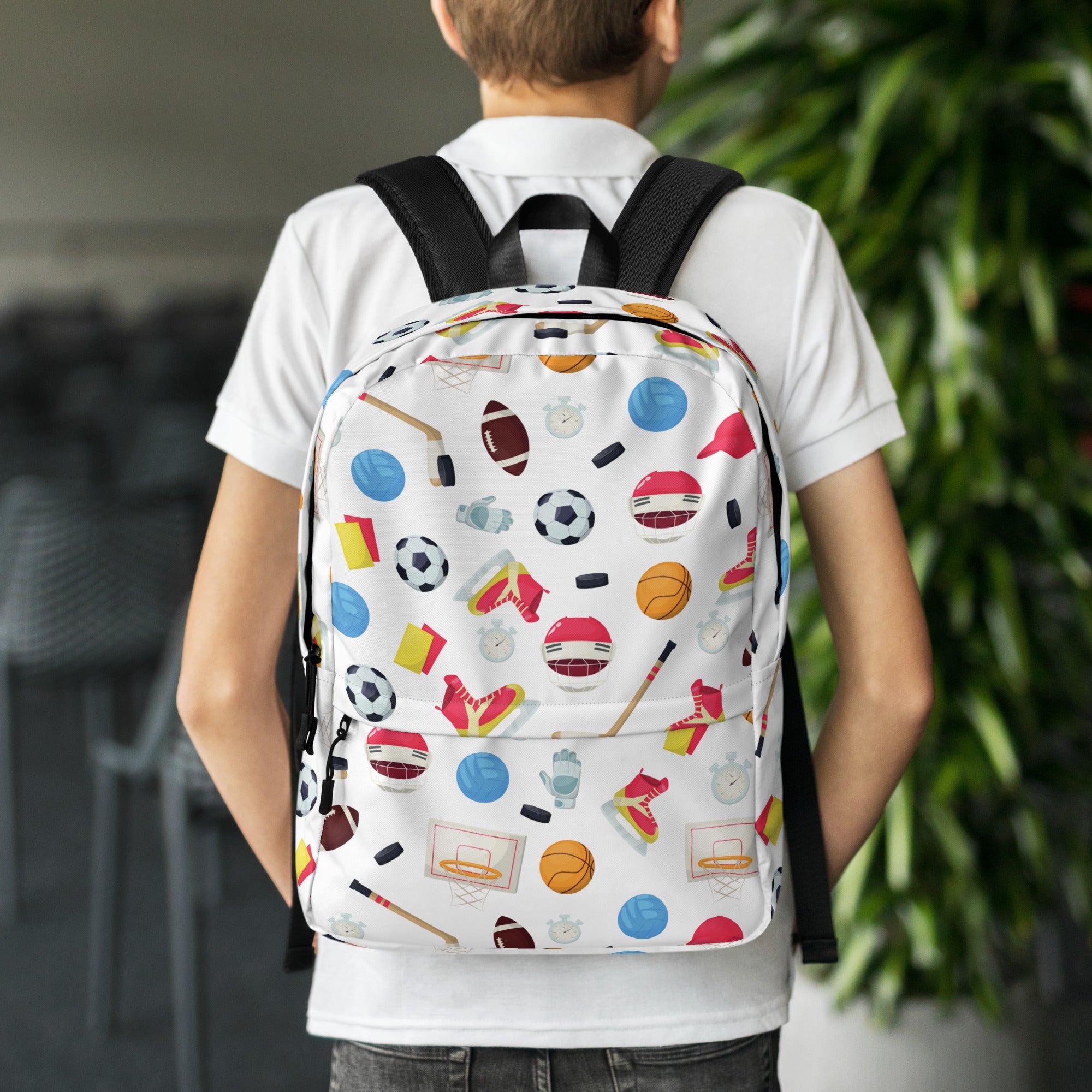 White kids sports themed backpack with black straps and colorful soccer ball basketball and hockey puck icons