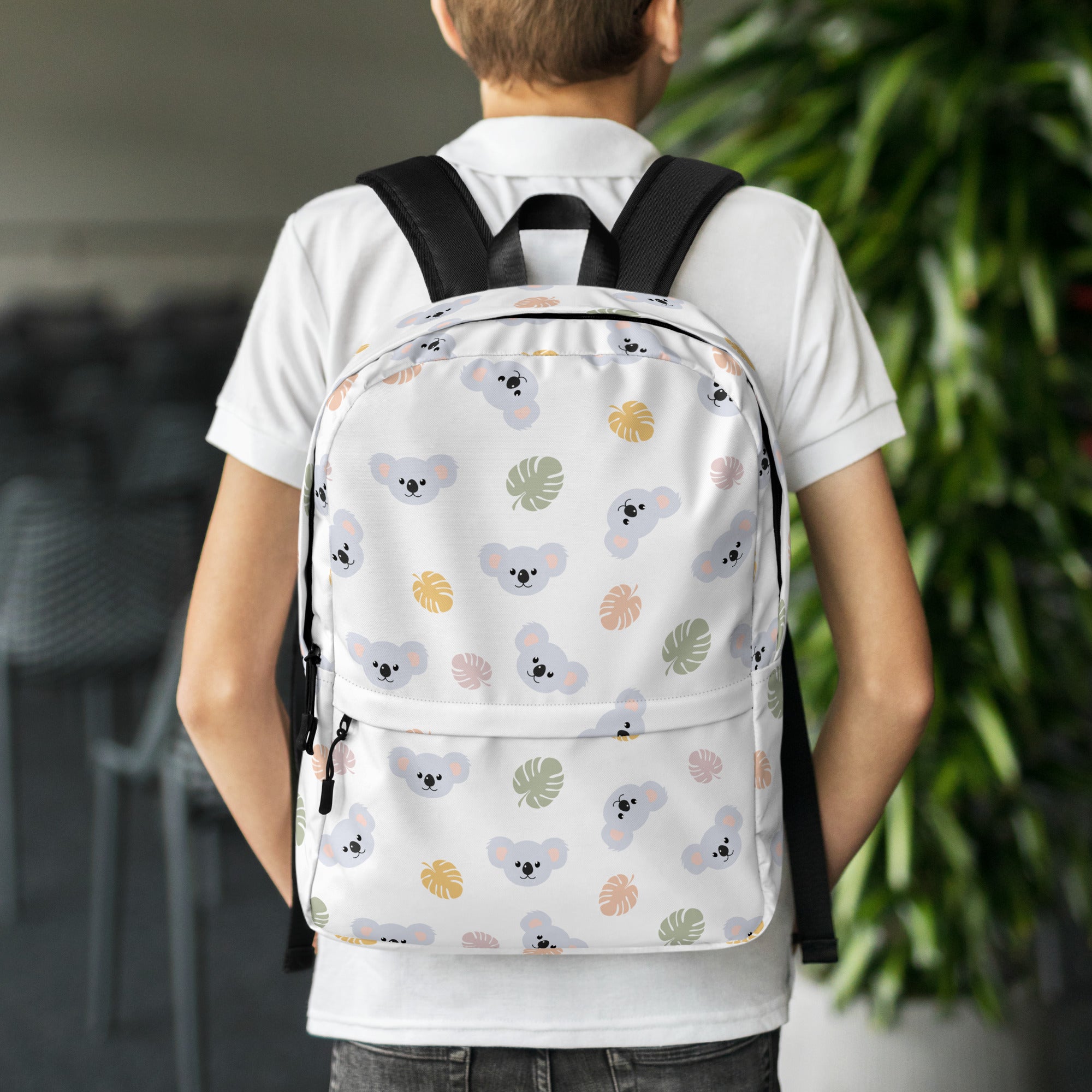 Girls koala bear backpack in white with black straps featuring a playful gray koala and pastel tropical leaf pattern