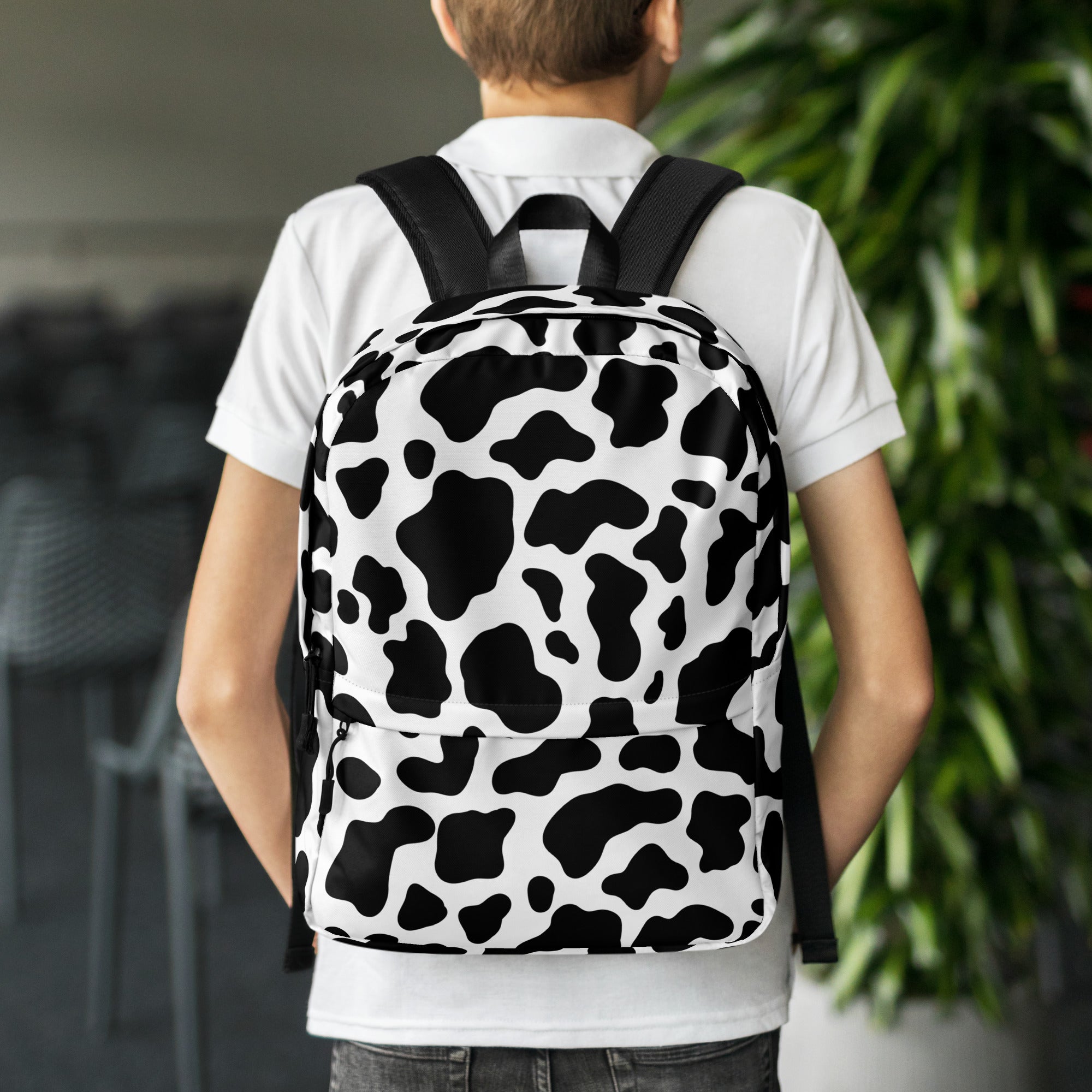 Kids cow print backpack featuring black and white cow pattern with black straps for comfortable wear