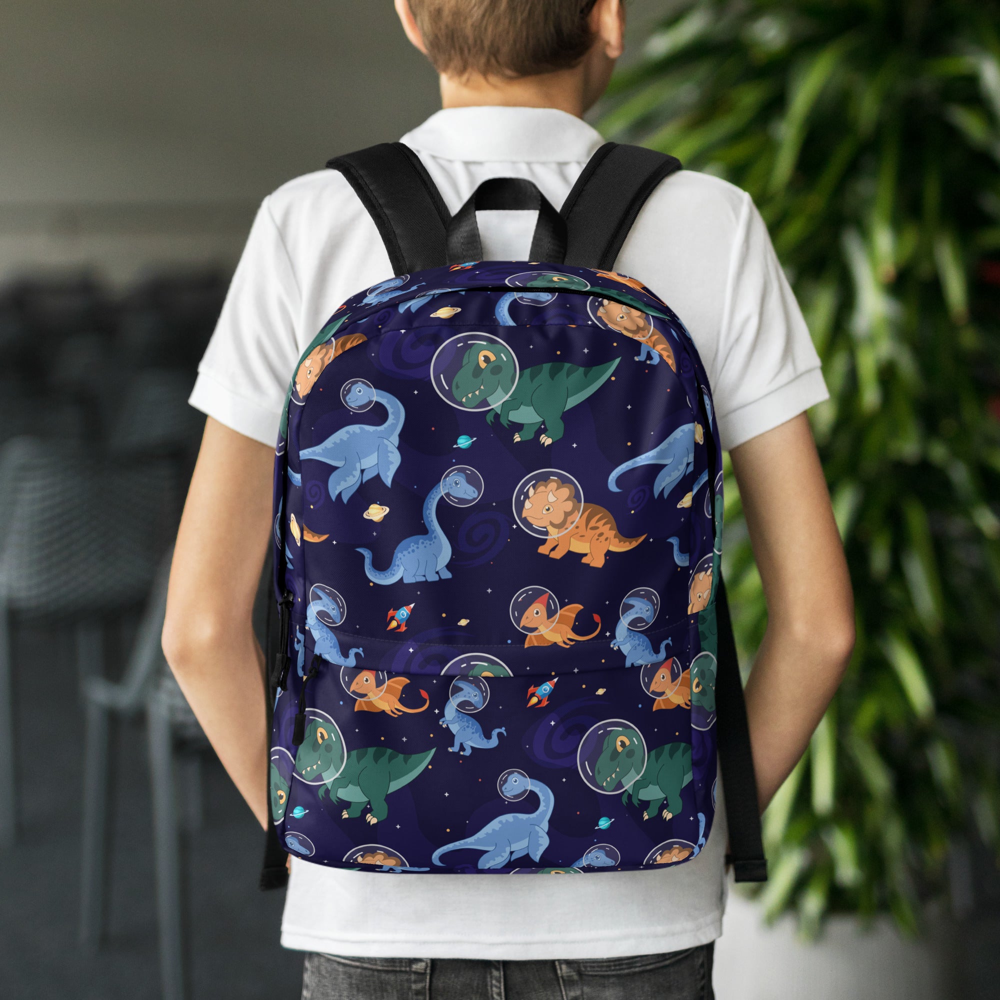 Navy blue kids space dinosaurs backpack with playful cartoon dinosaur pattern in space helmets on starry background