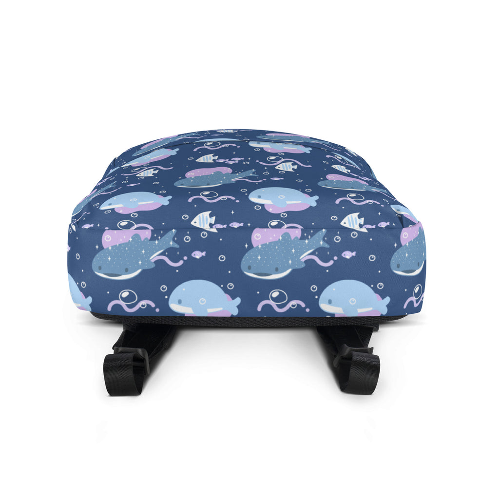 A navy blue girls whale shark backpack with a playful cartoon whale and fish pattern in light blue pink and white