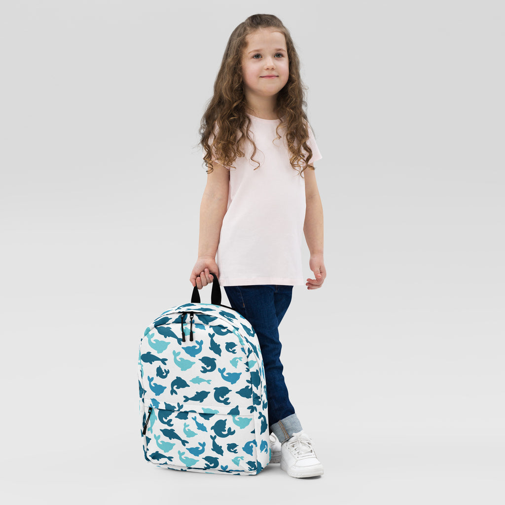 White kids dolphin print backpack featuring a playful teal and dark blue whale pattern for school use