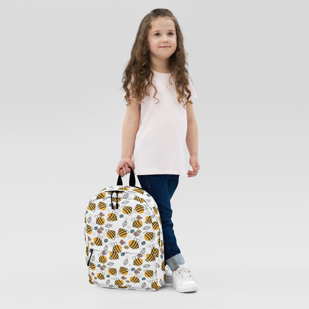 White kids floral bees backpack featuring a playful pattern of yellow black bees green leaves and purple flowers