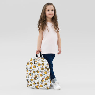 White kids floral bees backpack featuring a playful pattern of yellow black bees green leaves and purple flowers