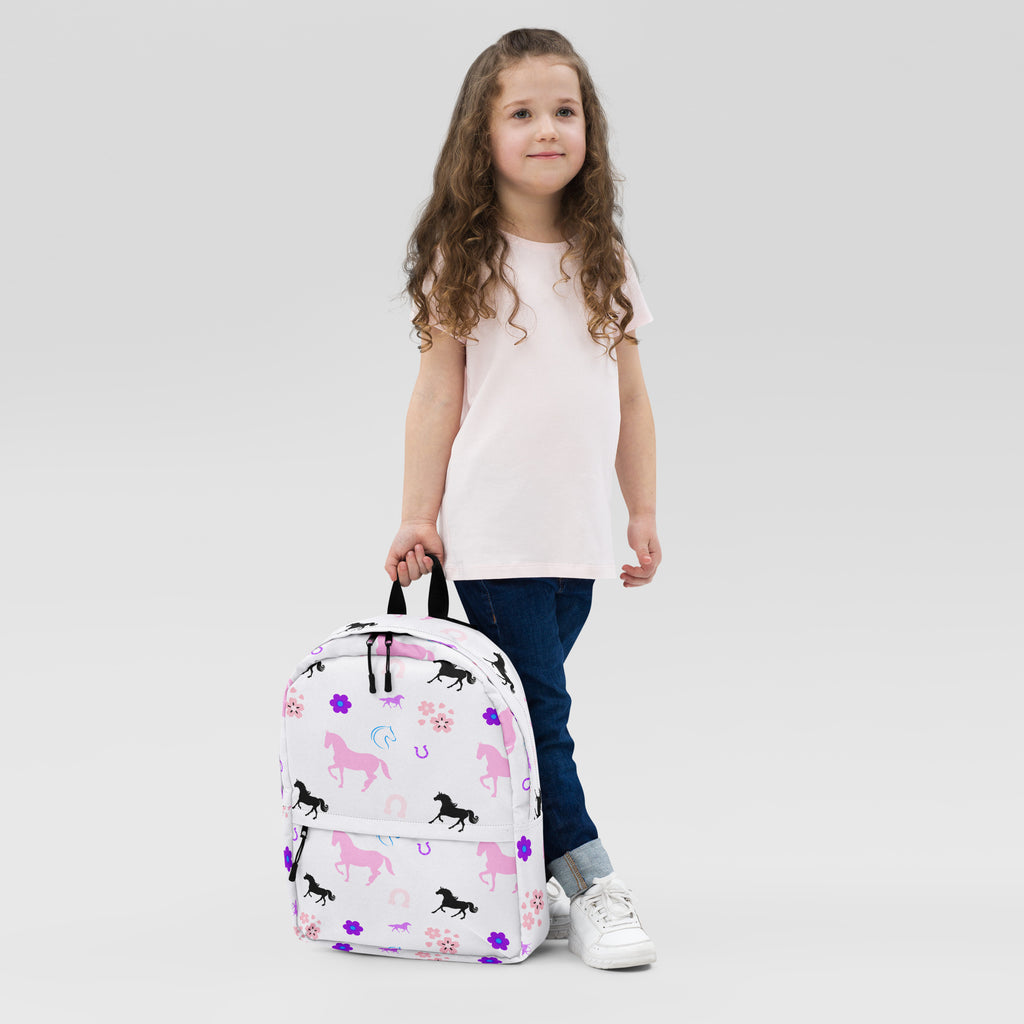 Girls horse print backpack white with pink and black horse patterns purple flowers and horseshoes on fabric surface