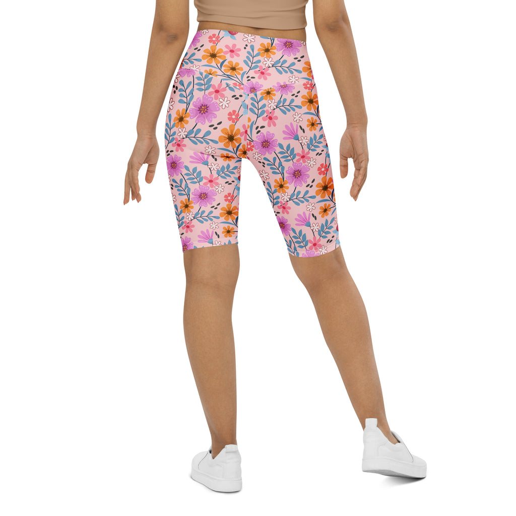 Women’s pink floral high waisted biker shorts with moisture wicking fabric and vibrant orange purple and blue blossoms