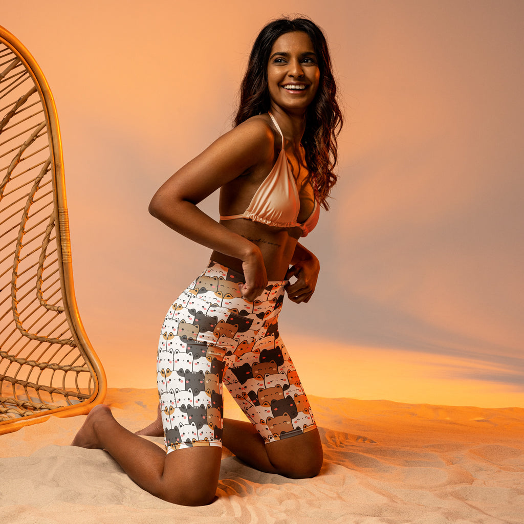Woman wearing high waisted moisture wicking biker shorts with playful cartoon cat face pattern in white gray black orange