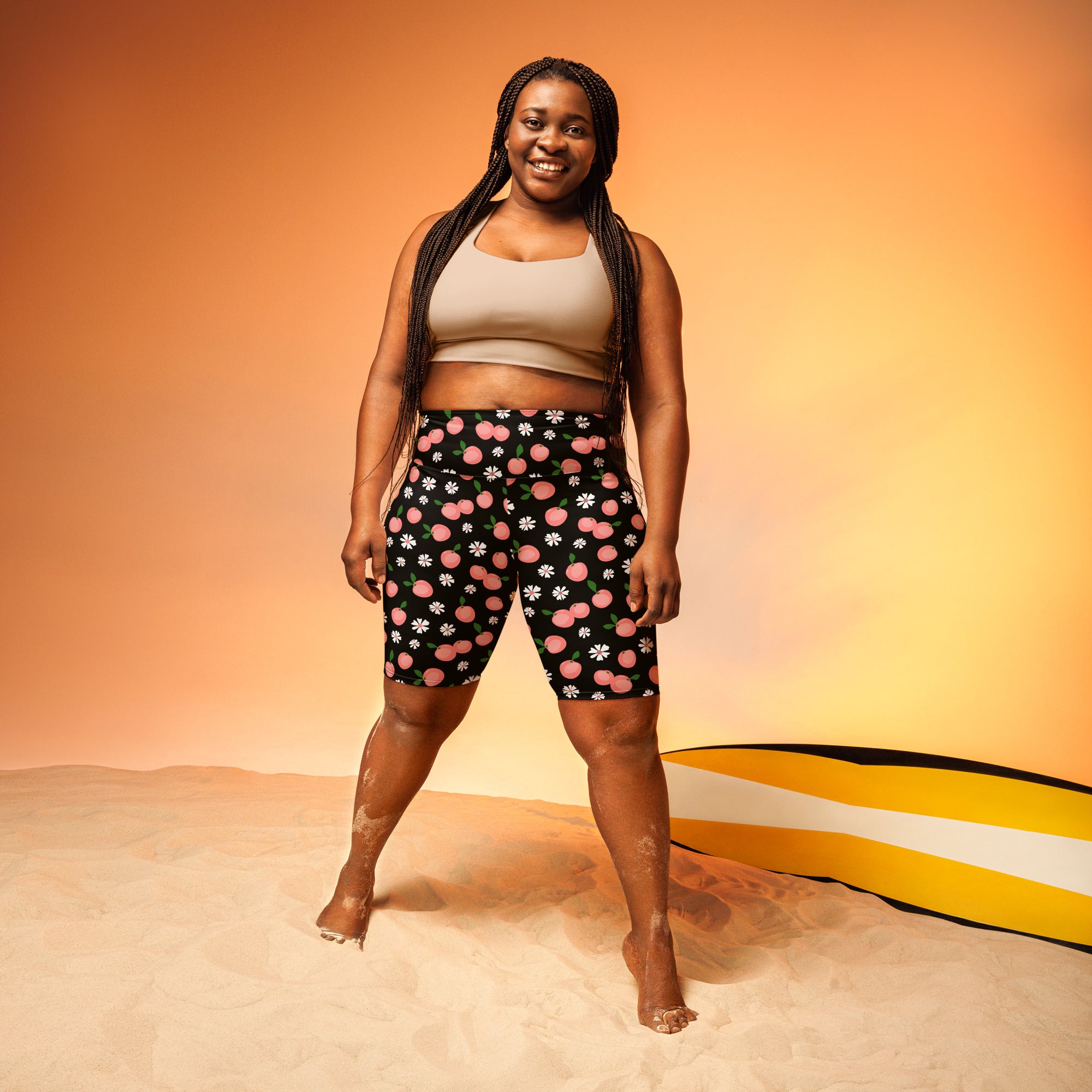 Women’s black high waisted moisture wicking biker shorts with playful pink peaches and white daisies pattern