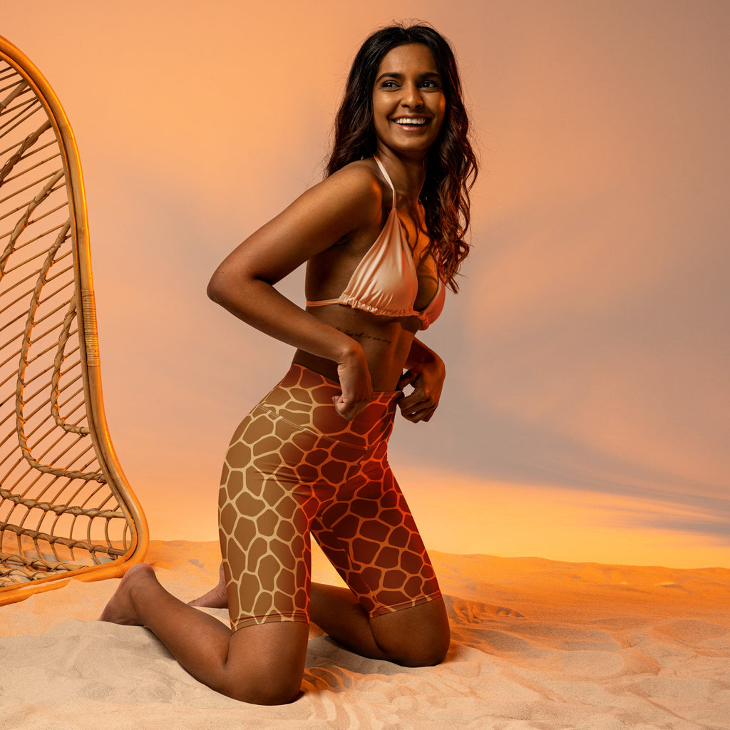 A woman wearing moisture wicking women’s giraffe print high waisted biker shorts with a peach swimsuit top