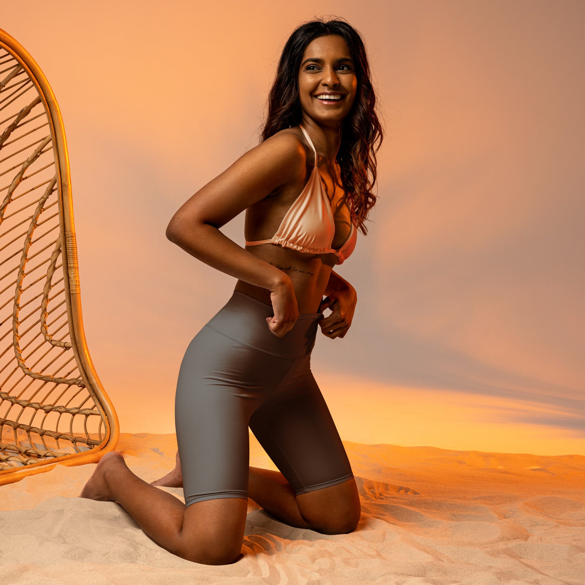 Woman wears metallic rose gold bikini top with thin straps and gray high waisted moisture wicking biker shorts