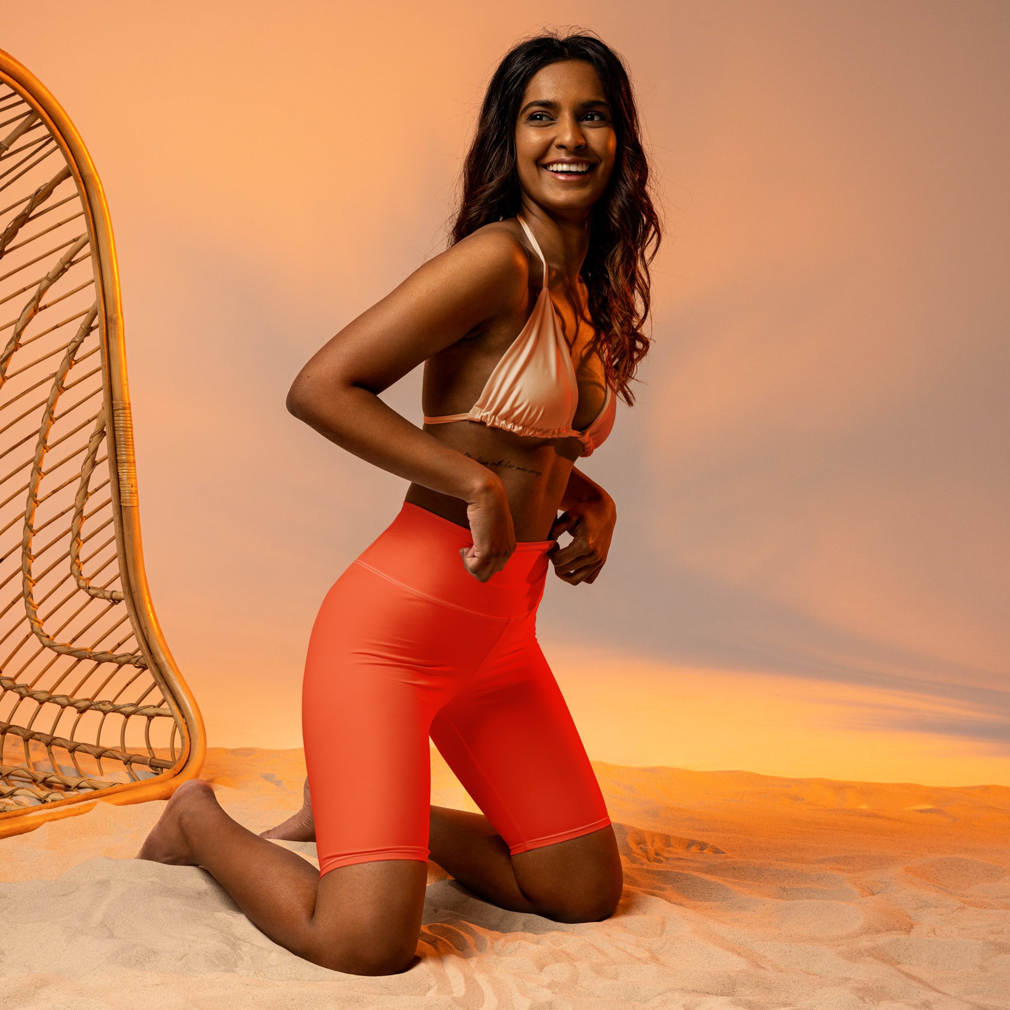 Woman wearing vibrant coral orange high waisted biker shorts with moisture wicking fabric and active fit design