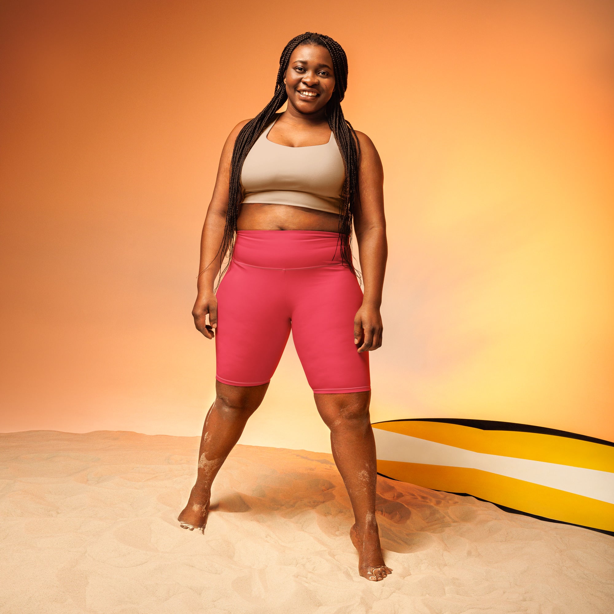 A woman wearing bright pink high waisted bike shorts with moisture wicking active fit paired with a beige crop top