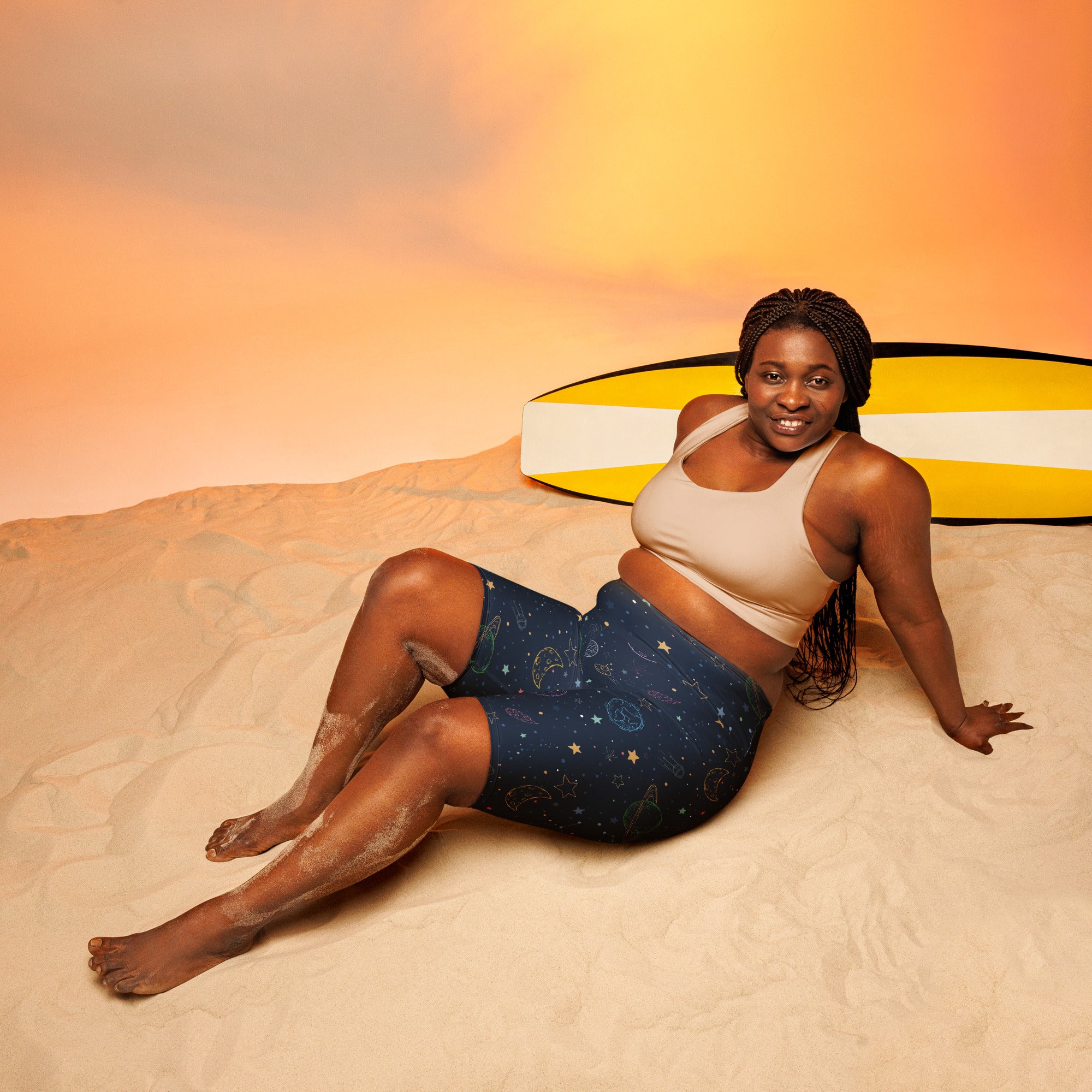 A woman wearing navy blue colorful galaxy space high waisted moisture wicking biker shorts with a beige sports bra