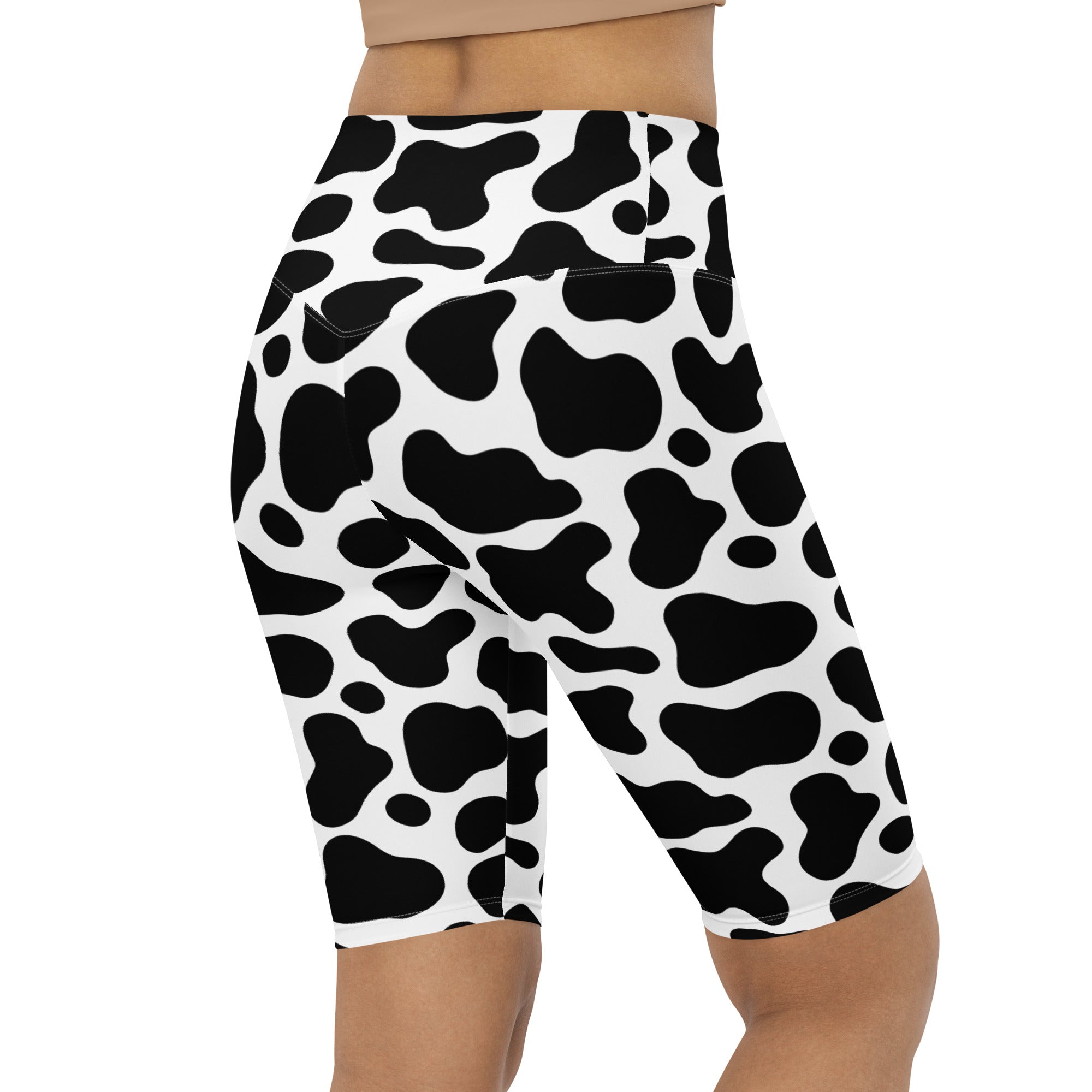 Women’s black and white cow print high waisted biker shorts with moisture wicking active fit fabric shown from the back