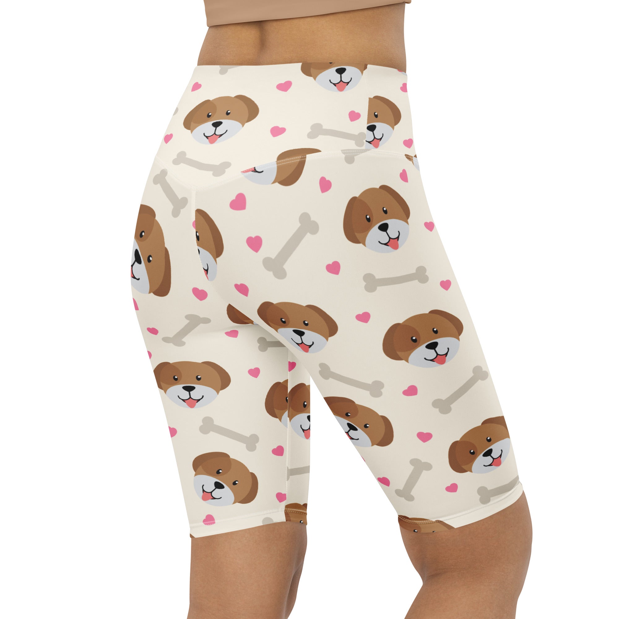 Cream-colored women’s high waisted biker shorts with brown cartoon dog faces pink hearts and gray bones moisture wicking