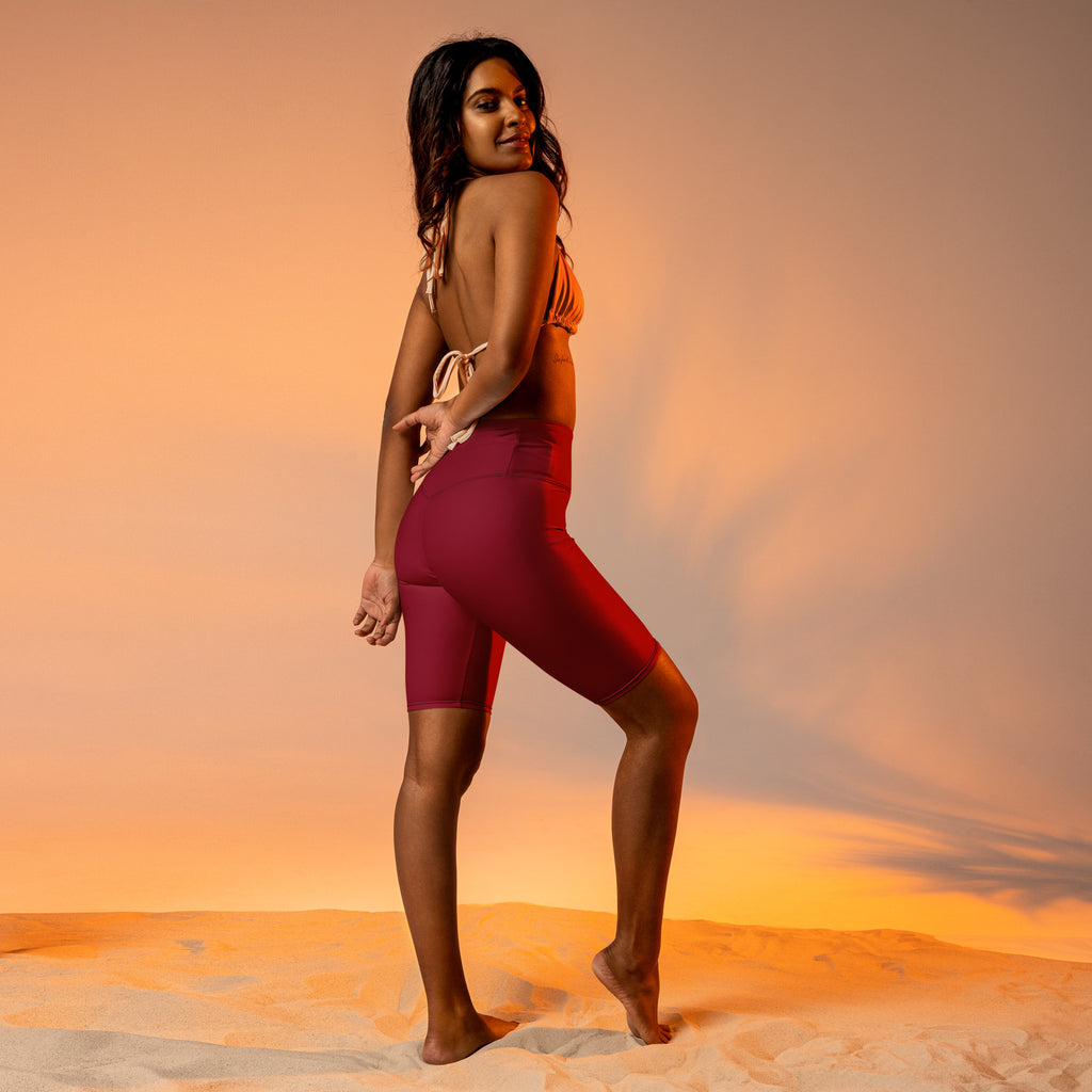 A woman wearing form-fitting burgundy high waisted biker shorts made of smooth moisture wicking fabric