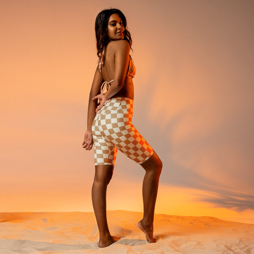 A woman wearing a beige and white checkered two-piece swimsuit with a tie-back top and high waisted moisture wicking biker shorts