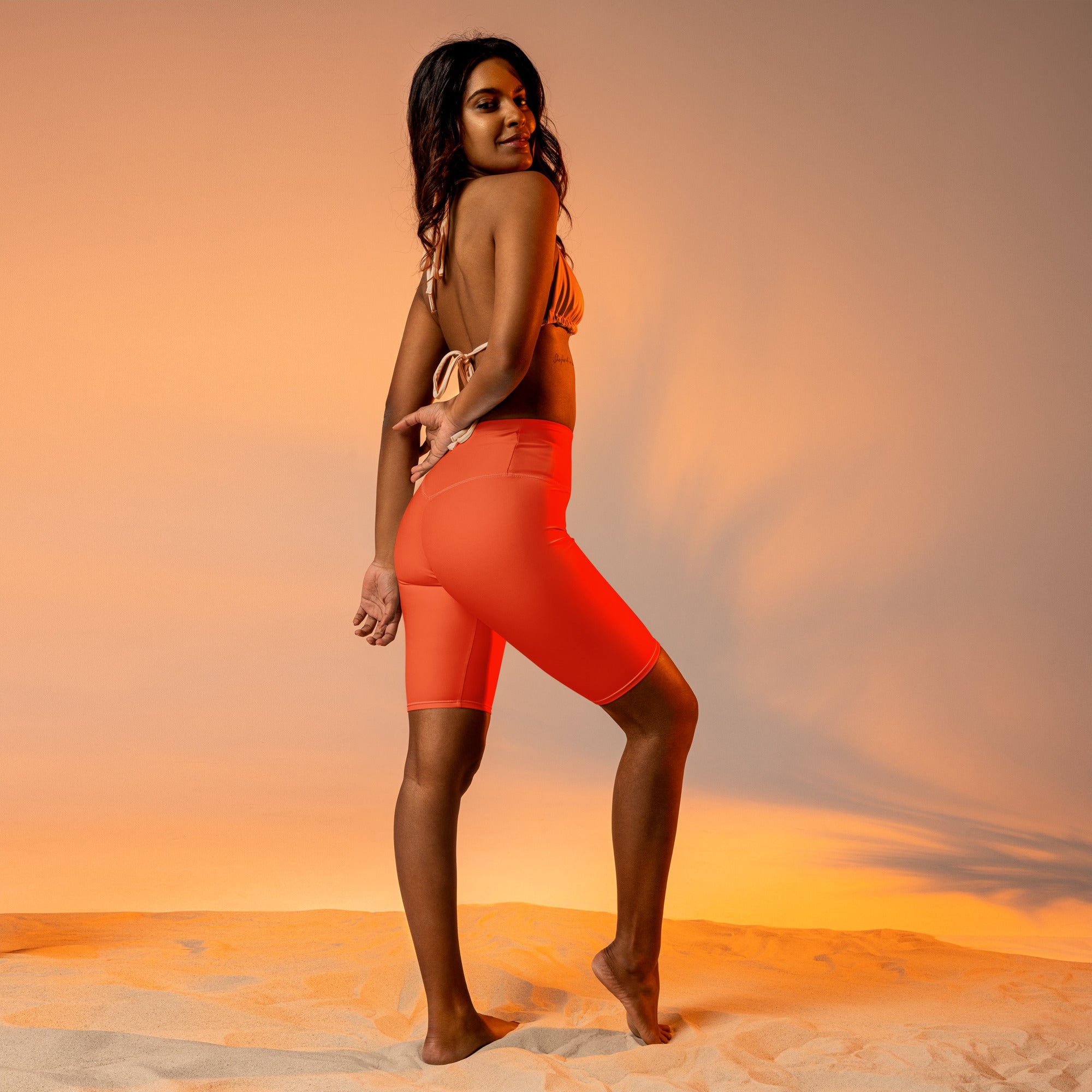 Vibrant coral orange high waisted bike shorts with moisture wicking fabric and subtle side pockets for active fit use
