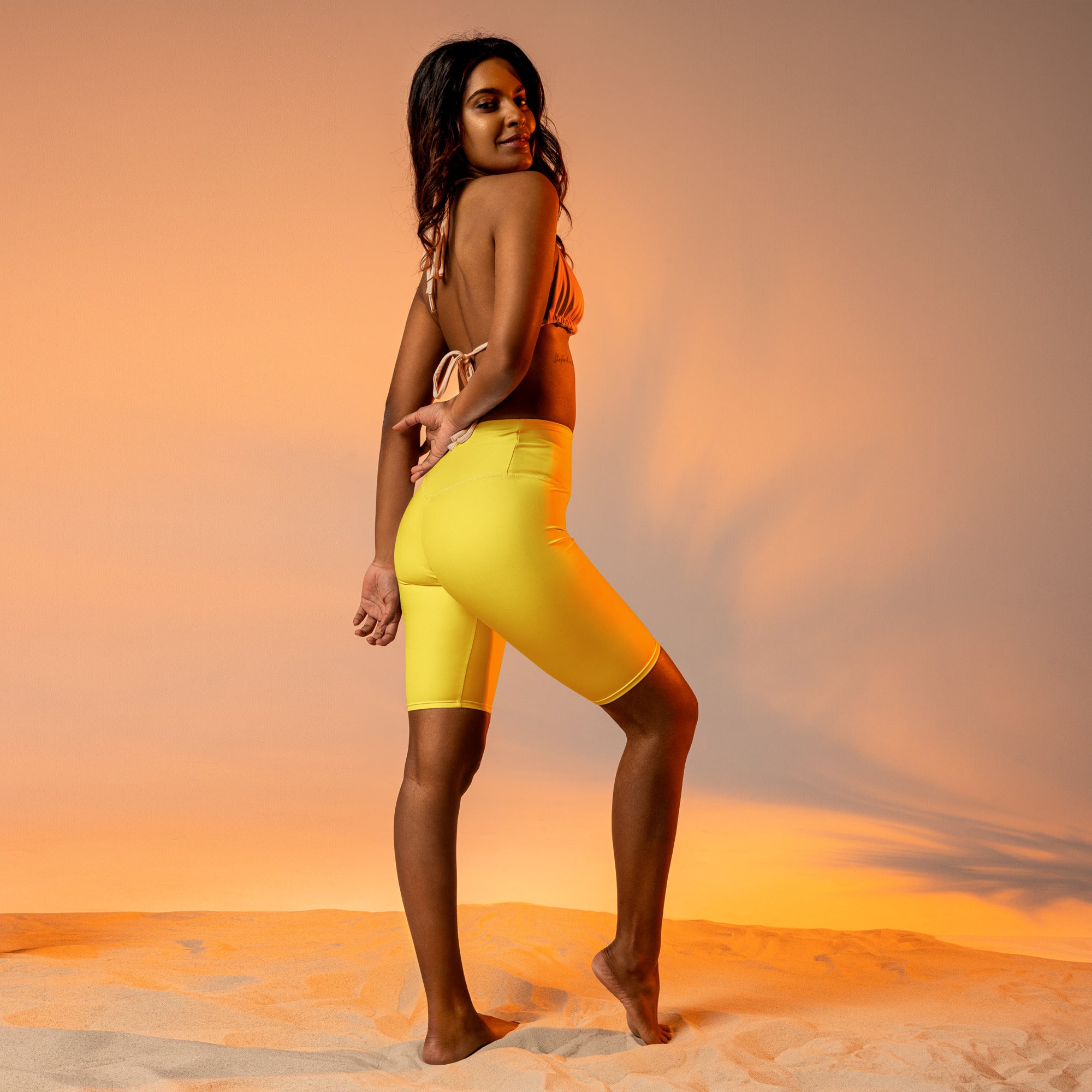 Women’s bright yellow high waisted biker shorts with a moisture wicking active fit and sleek form fitting design