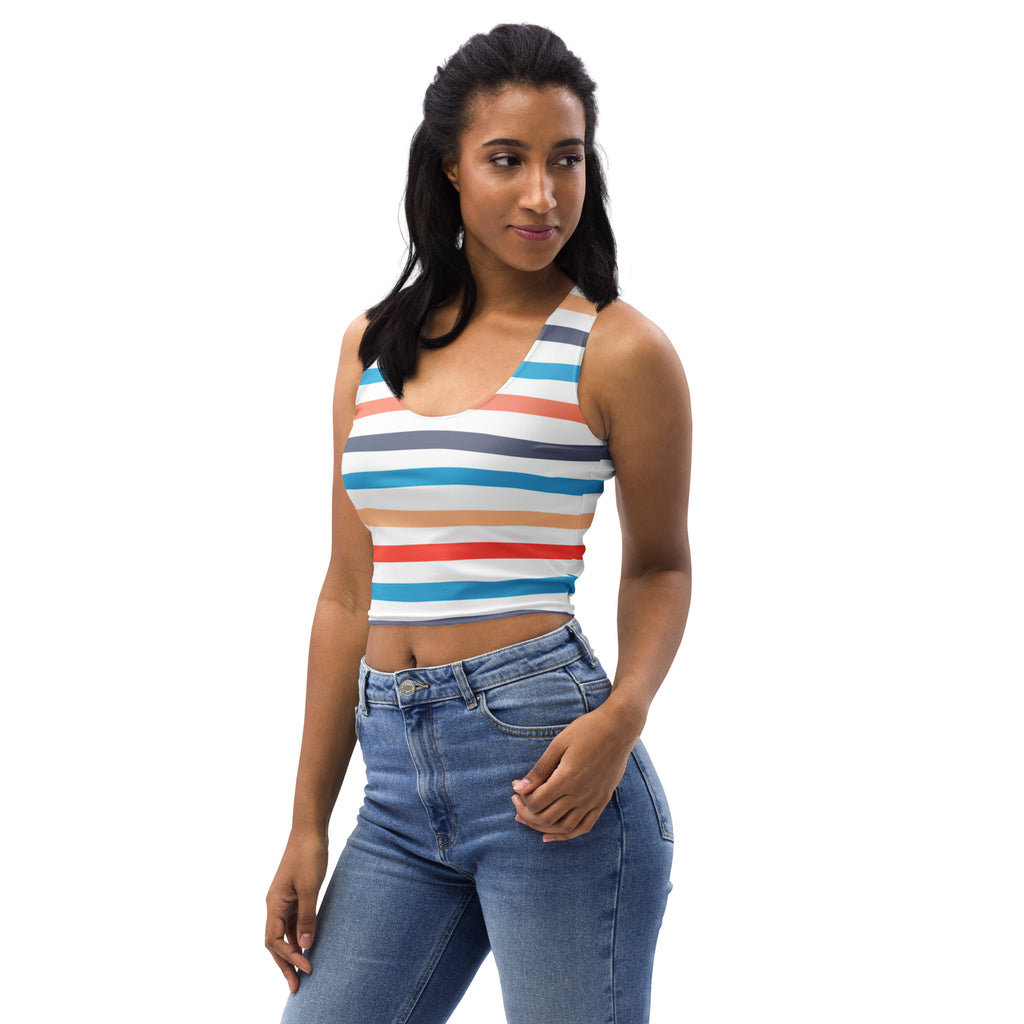 A woman wearing a women’s retro sunset stripes buttery soft crop top with colorful white blue red and gray horizontal bands
