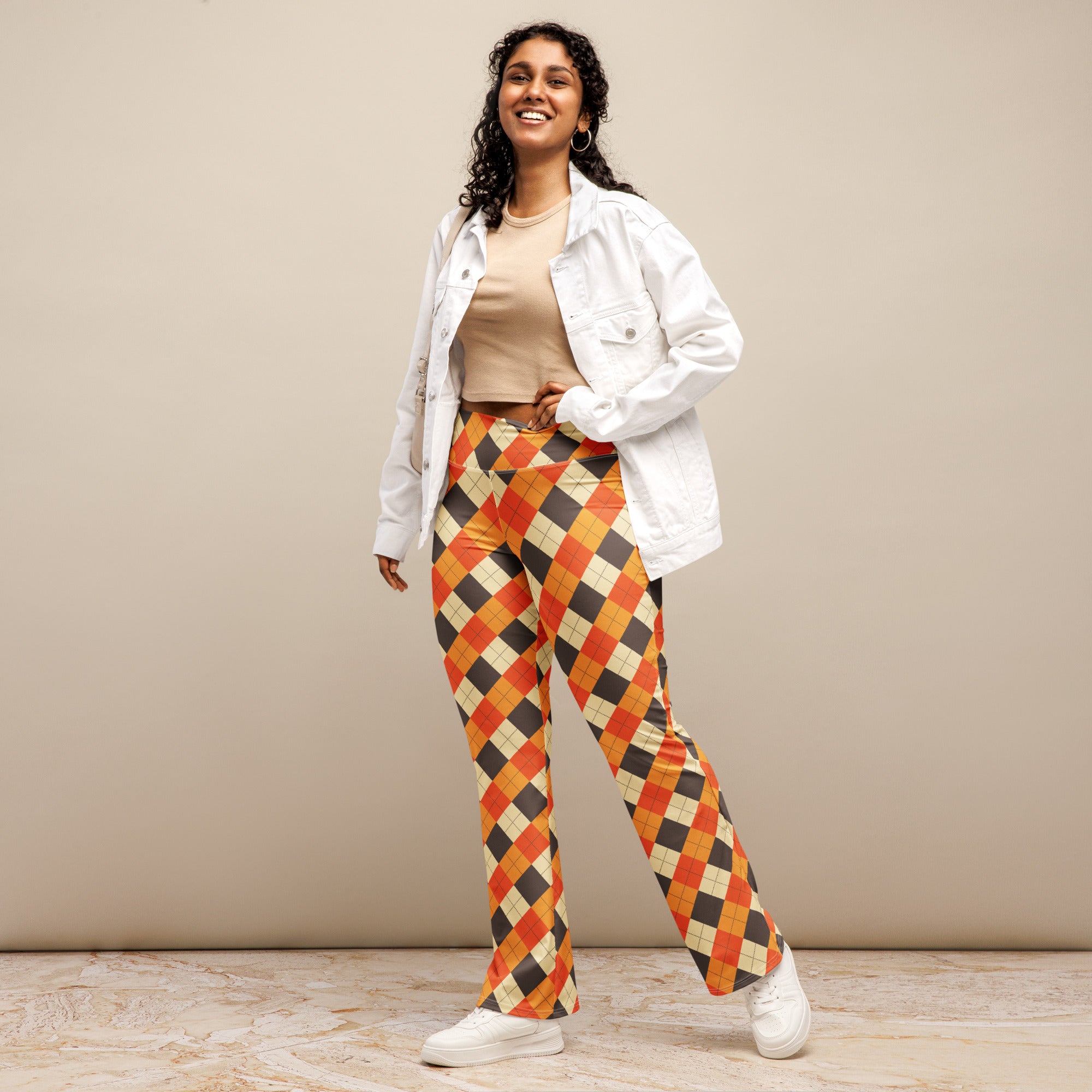 A pair of women’s fall argyle high waist flare legging pants in bold orange black and cream pattern