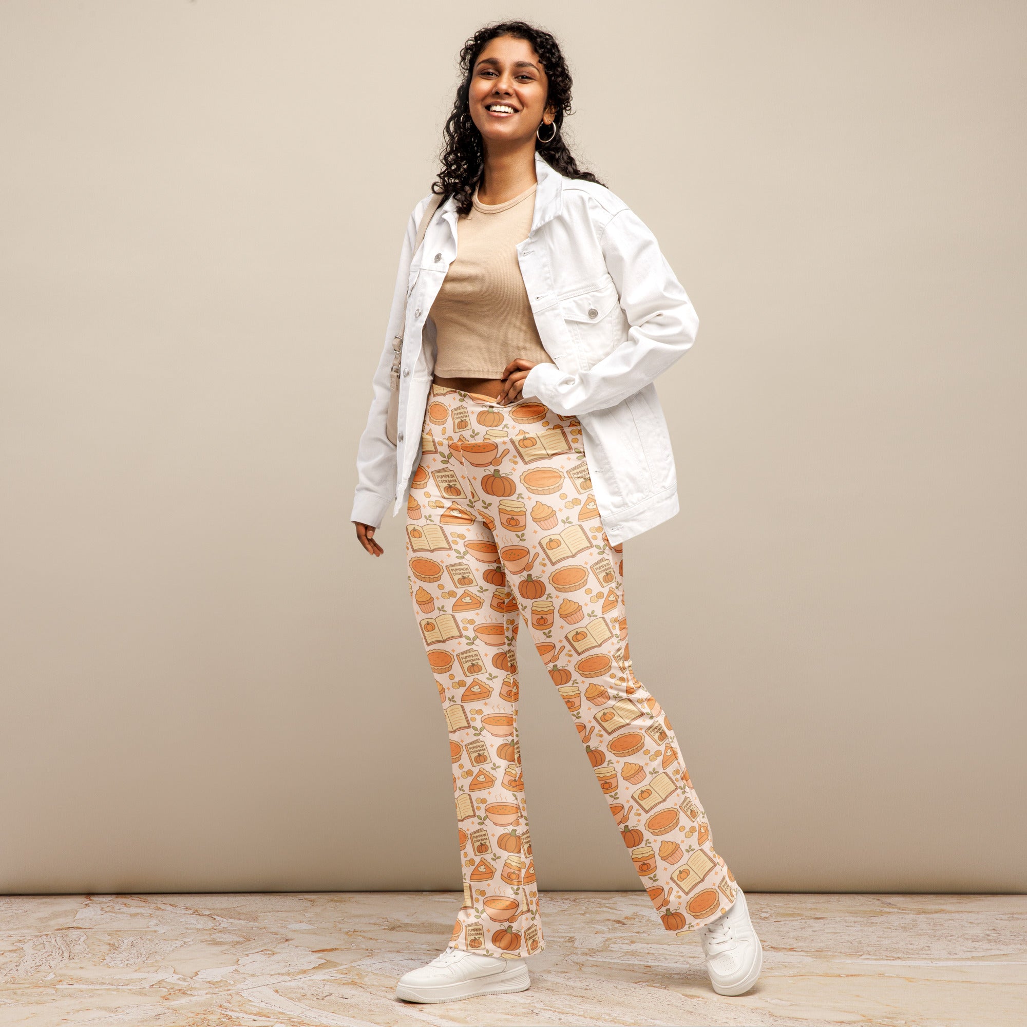 Cream-colored women’s high waist flare legging pants with playful orange pumpkins books and autumn food pattern