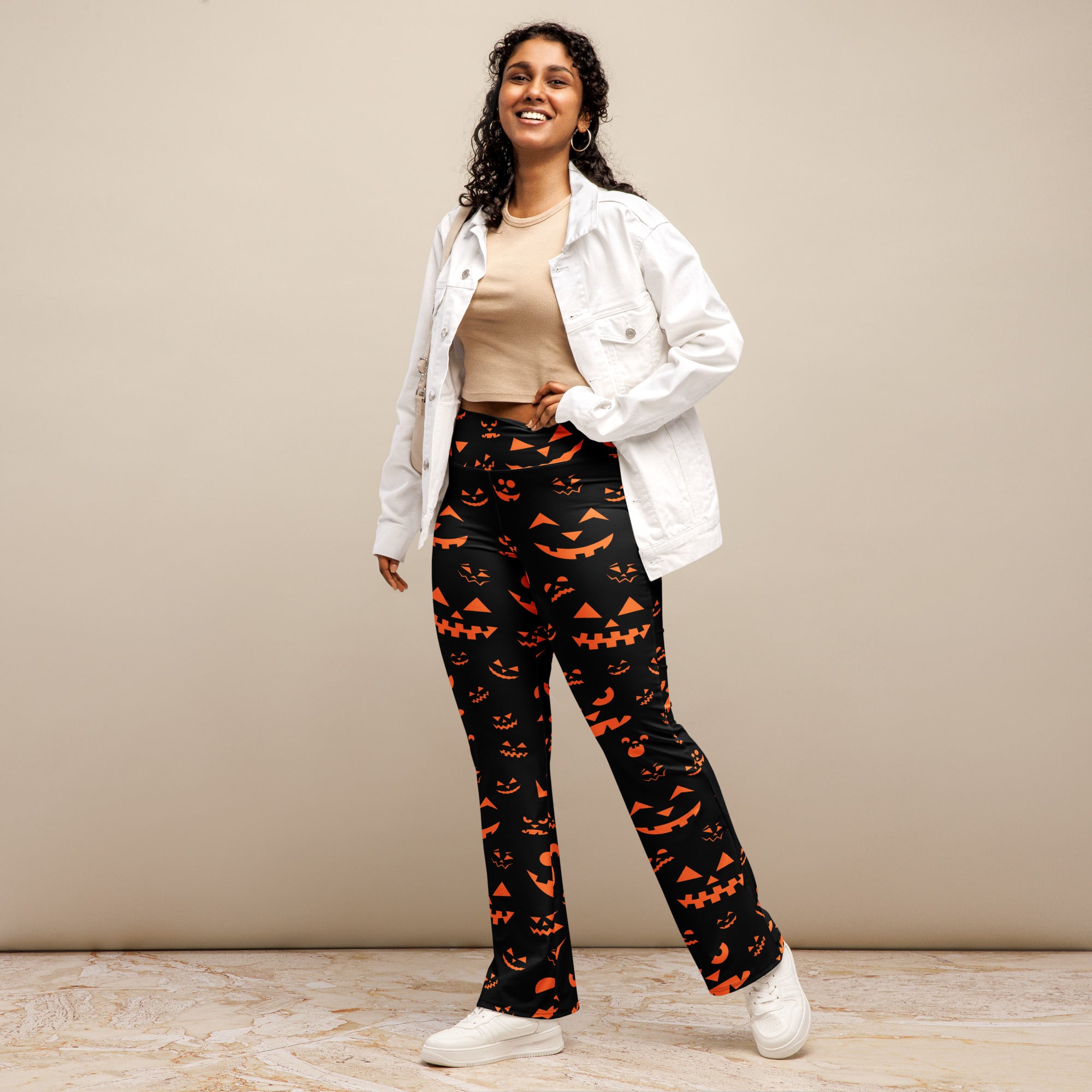 Women’s black high waist flare legging pants with orange jack o lantern faces printed for halloween wear