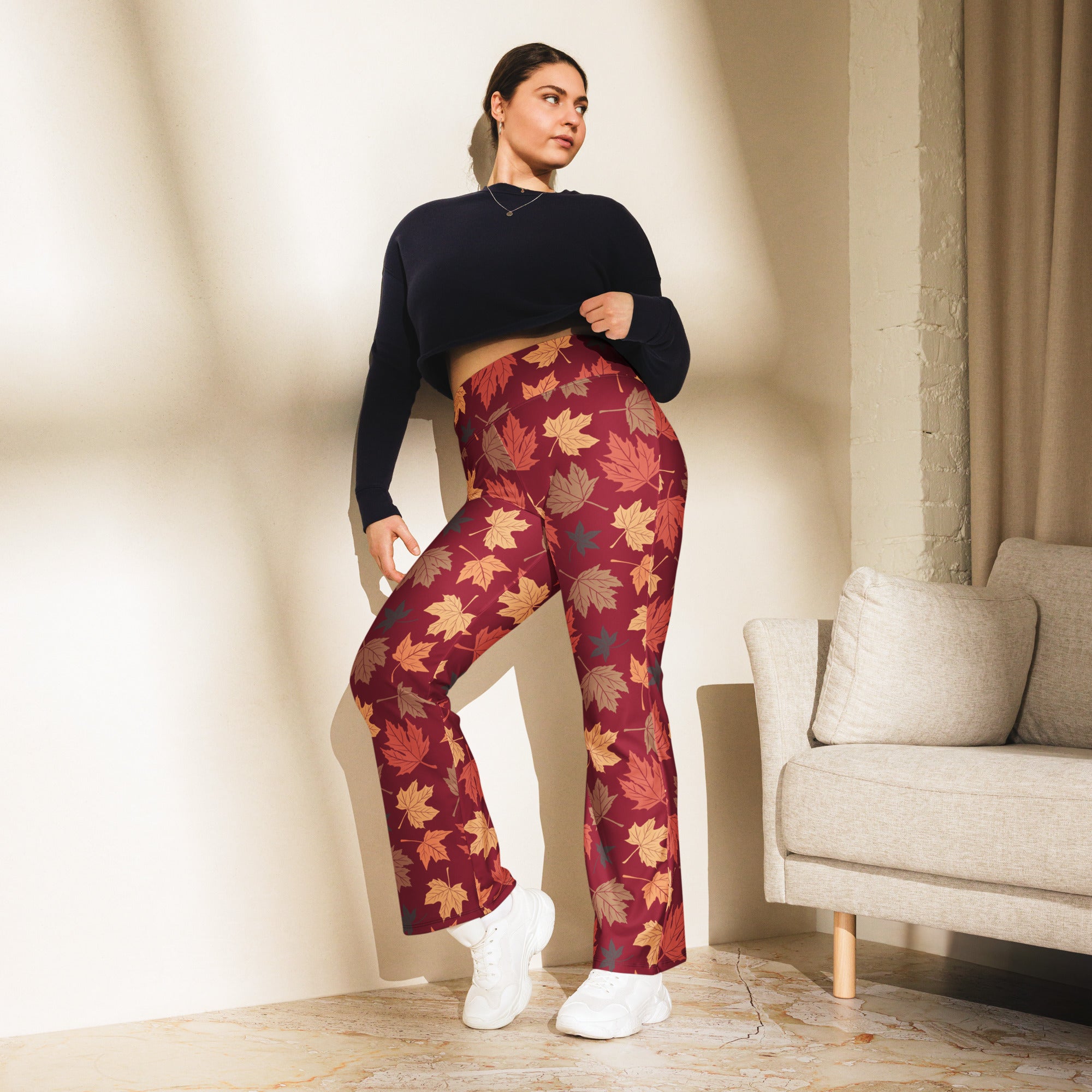 Plus-size woman wearing maroon high waist flare leggings with vibrant orange yellow and brown autumn leaf pattern