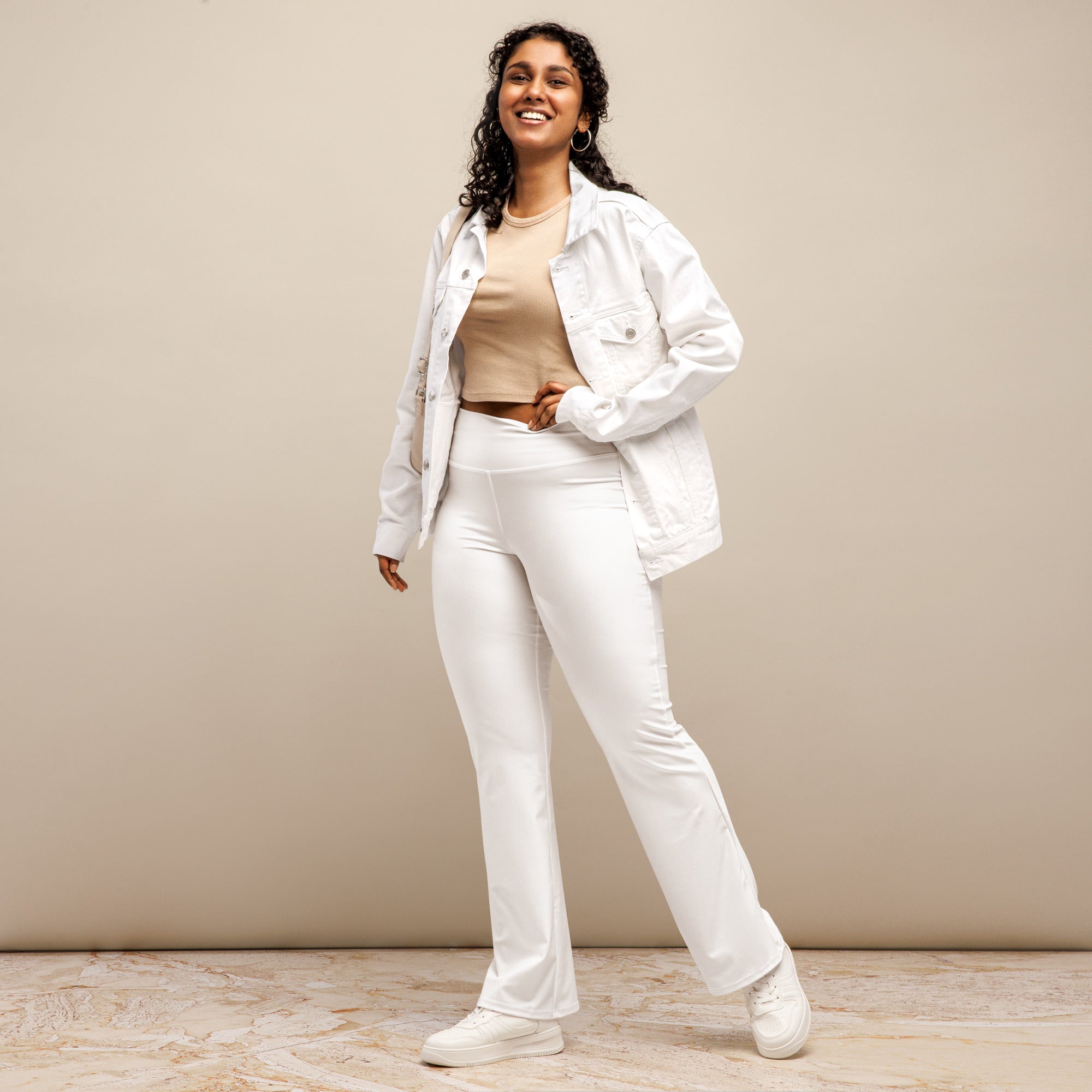 White denim jacket with button closures and flap pockets paired with women’s white high waist flare legging pants