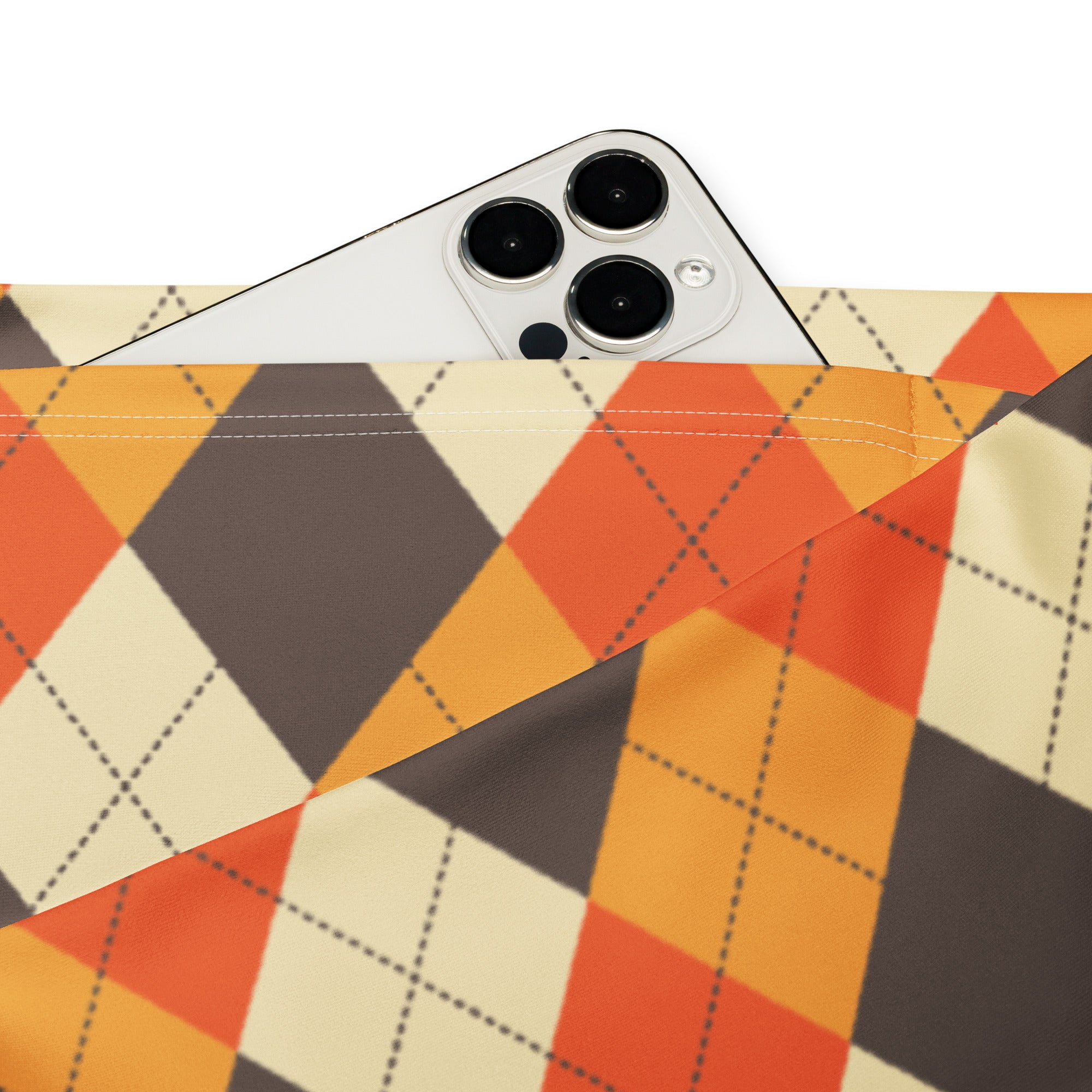 A white iphone with triple camera peeking from an orange beige and dark gray argyle fabric pouch in women’s fall high waist flare leggings