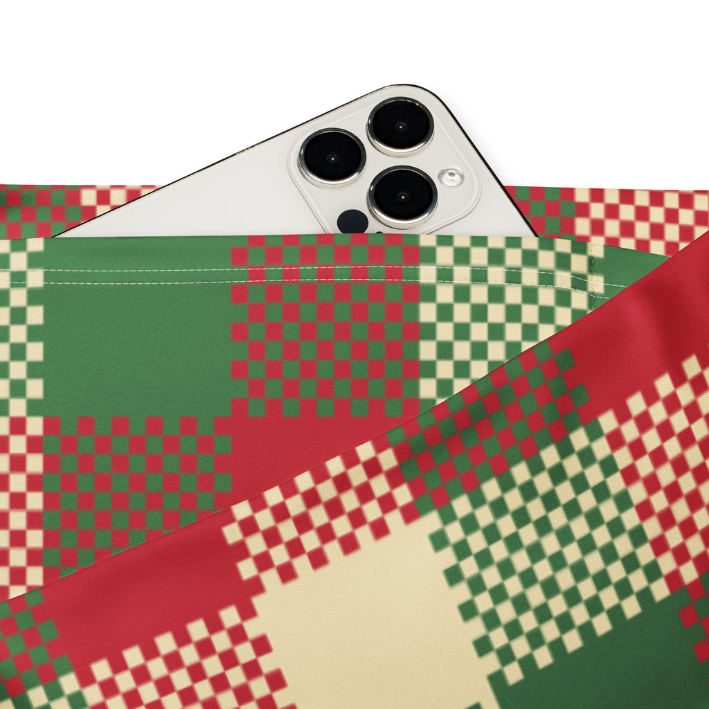 A white iphone with triple camera rests on a red green cream pixelated fabric pouch under womens christmas plaid leggings