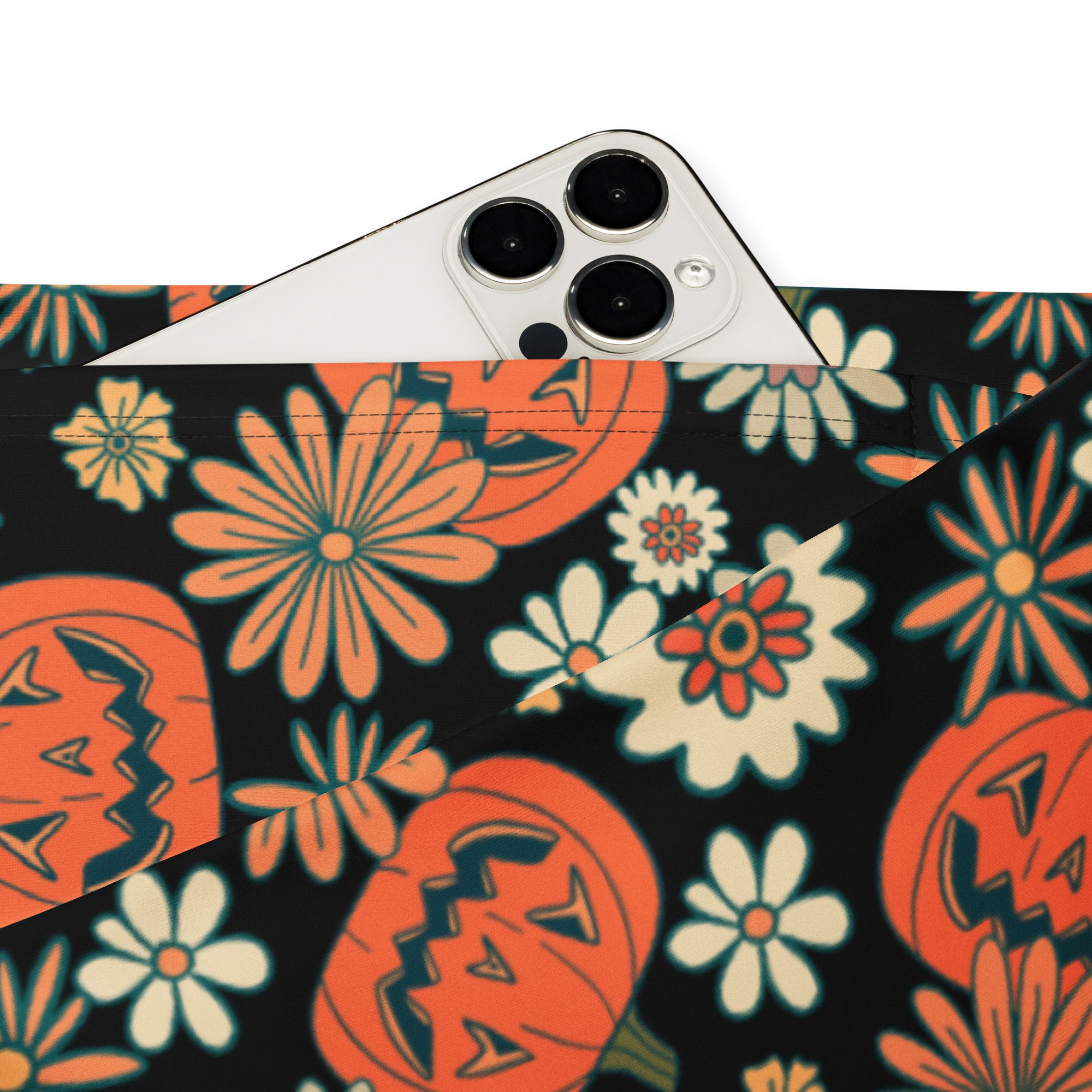 A black fabric pouch with vibrant halloween pattern featuring orange jack-o-lanterns and colorful flowers