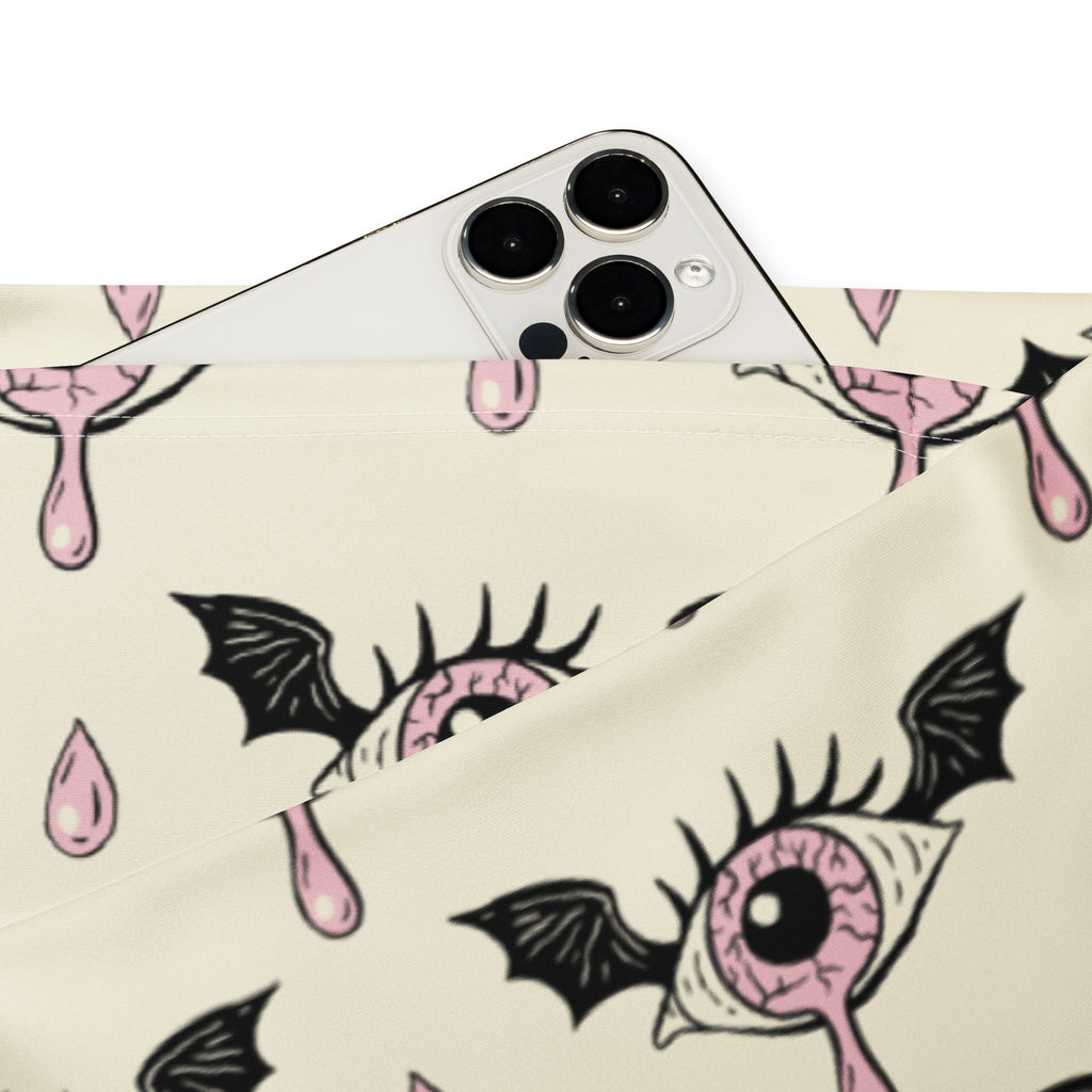 A cream fabric pouch with a gothic eyeball bat pattern featuring black wings and pink droplets