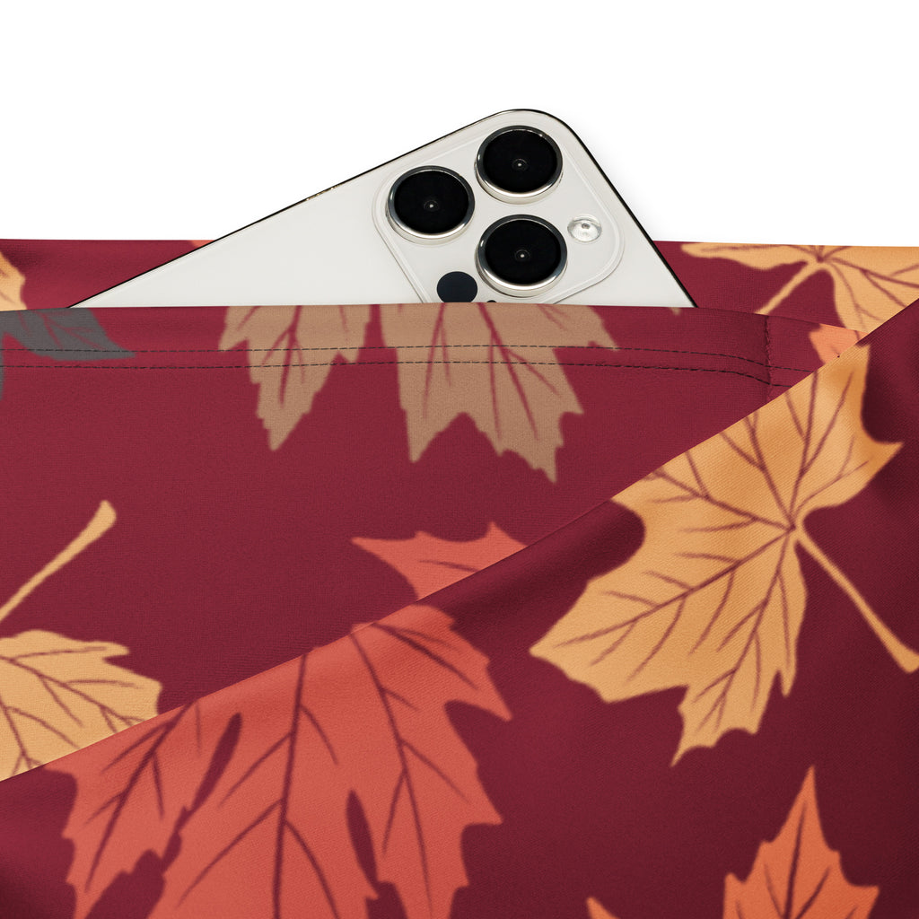 A maroon fabric pouch with vibrant orange and gold autumn leaf pattern holding a white smartphone pocket