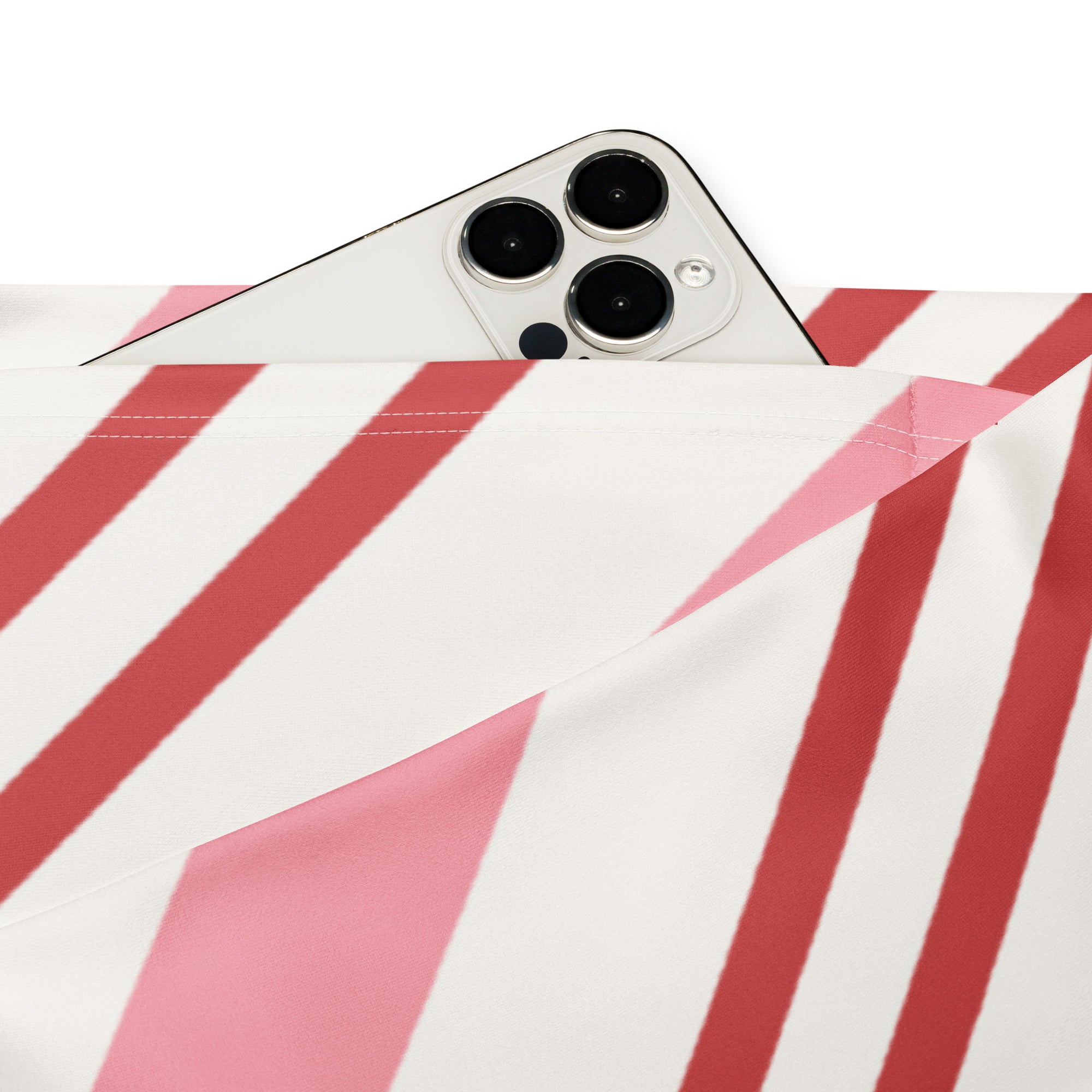 A white iphone with triple-camera peeking from beneath women’s pink candy cane stripes high waist flare leggings