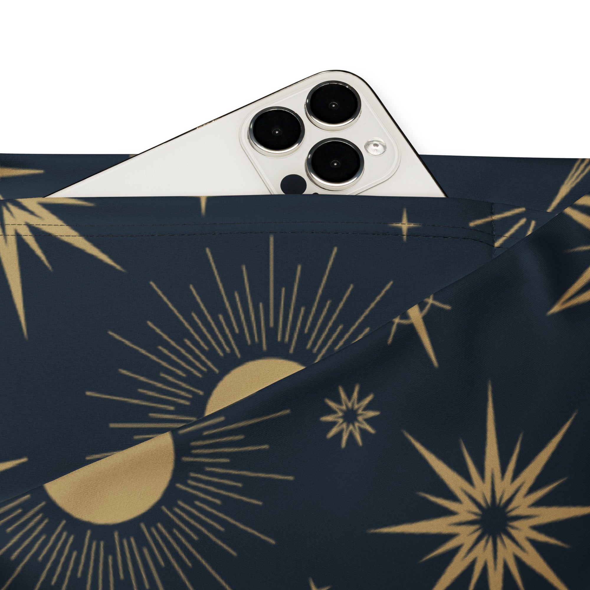A navy blue fabric pouch with a gold celestial sun and moon pattern holding a white smartphone next to women’s high waist flare legging pants