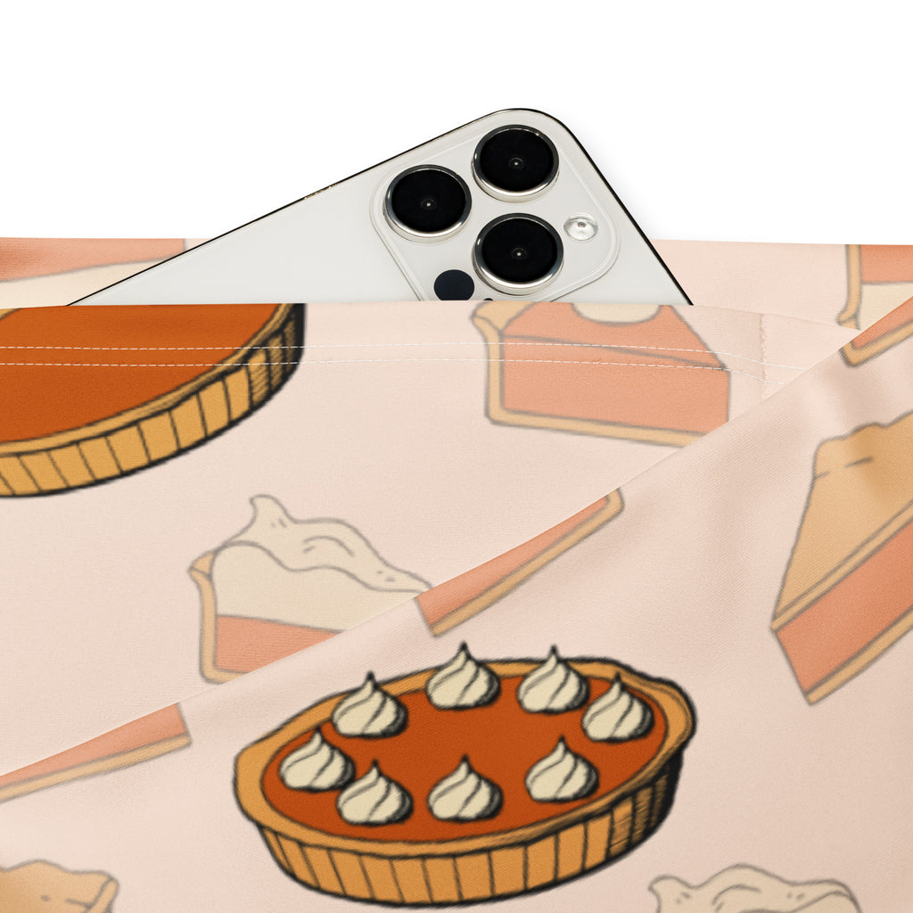 A white iphone with triple-camera rests on a light pink pumpkin pie pouch beside women’s pumpkin pie thanksgiving leggings