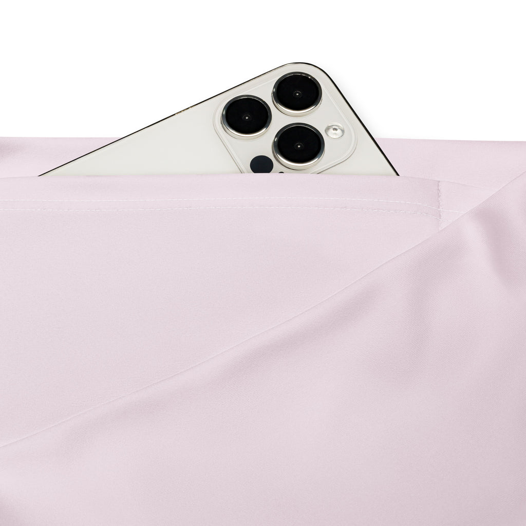 A sleek white iphone with triple-camera peeks from the soft pink fabric pocket of women’s light pink high waist flare leggings