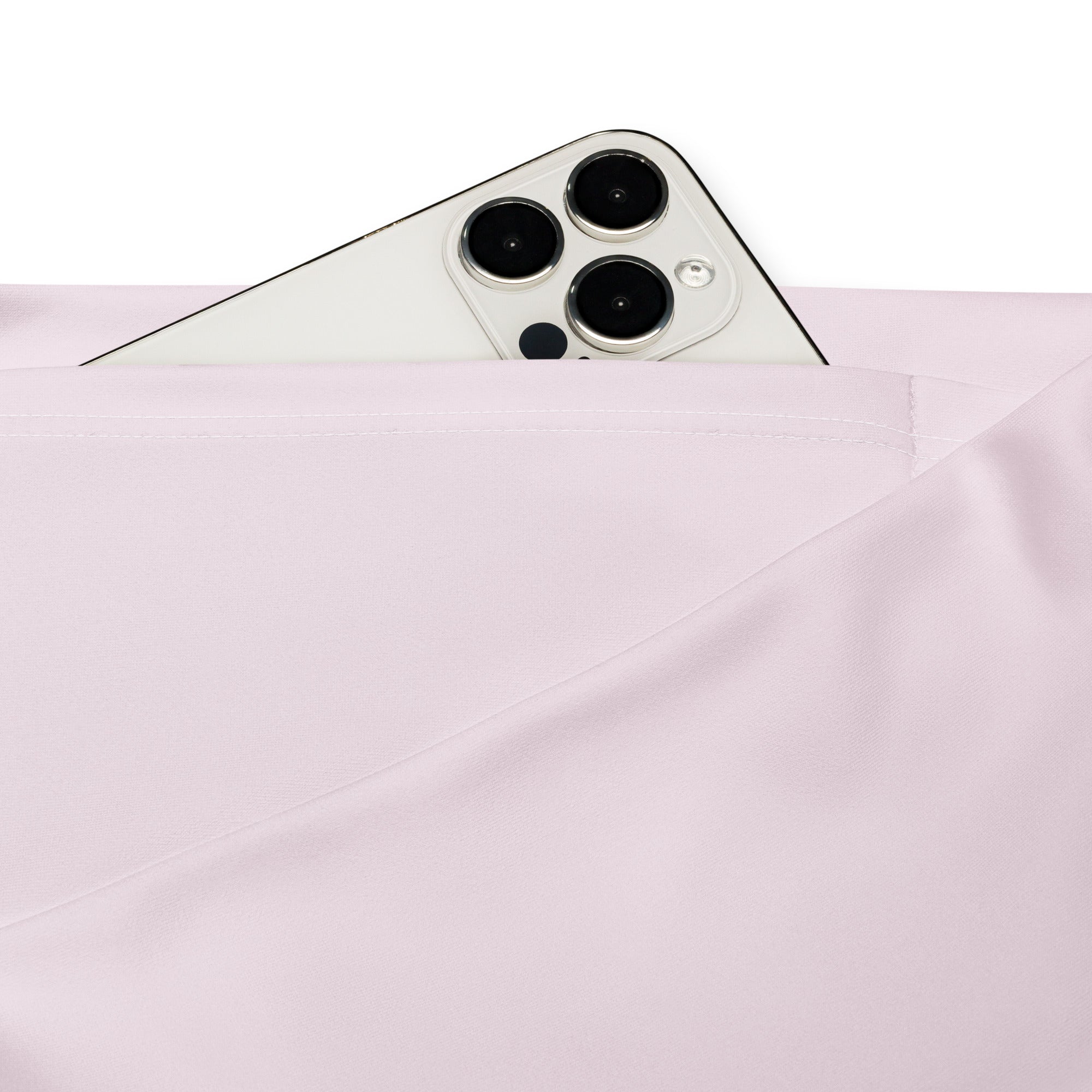 A sleek white iphone with triple-camera peeks from the soft pink fabric pocket of women’s light pink high waist flare leggings