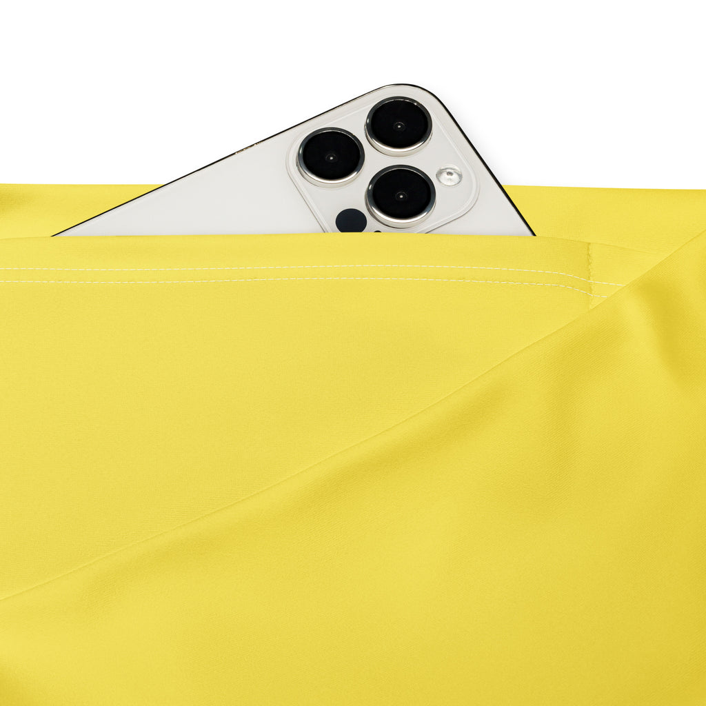 A white iphone with triple-camera peeking from the pocket of women’s yellow high waist flare legging pants